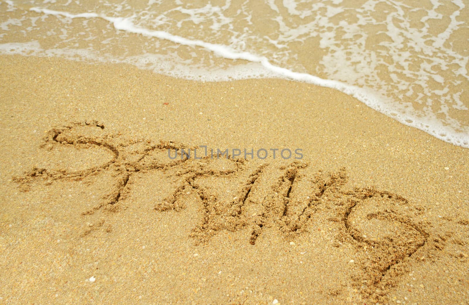 A warm tropical beach for spring break concept and spring written in the sand 