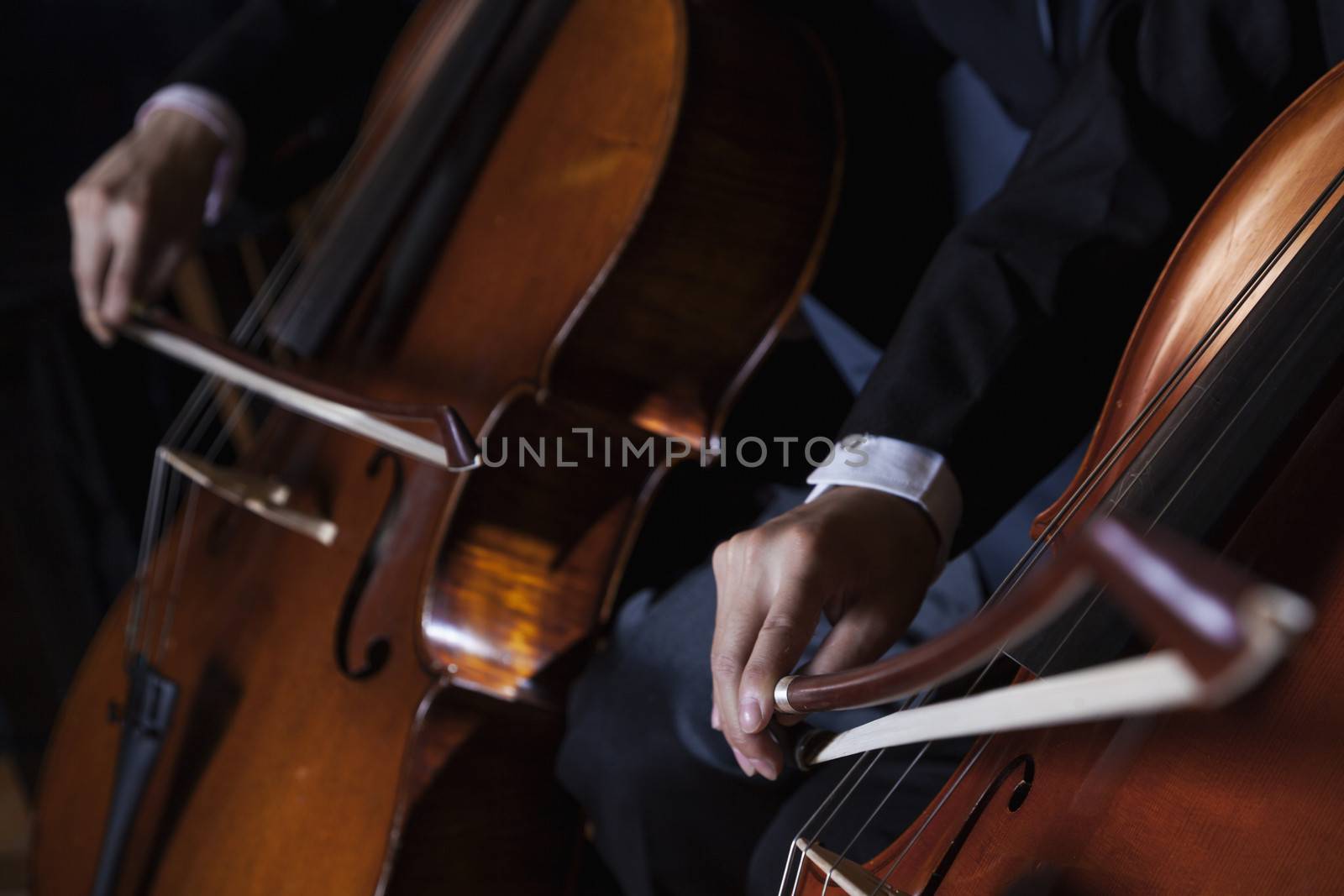 Close-up of midsection of two cellists playing the cello during a performance