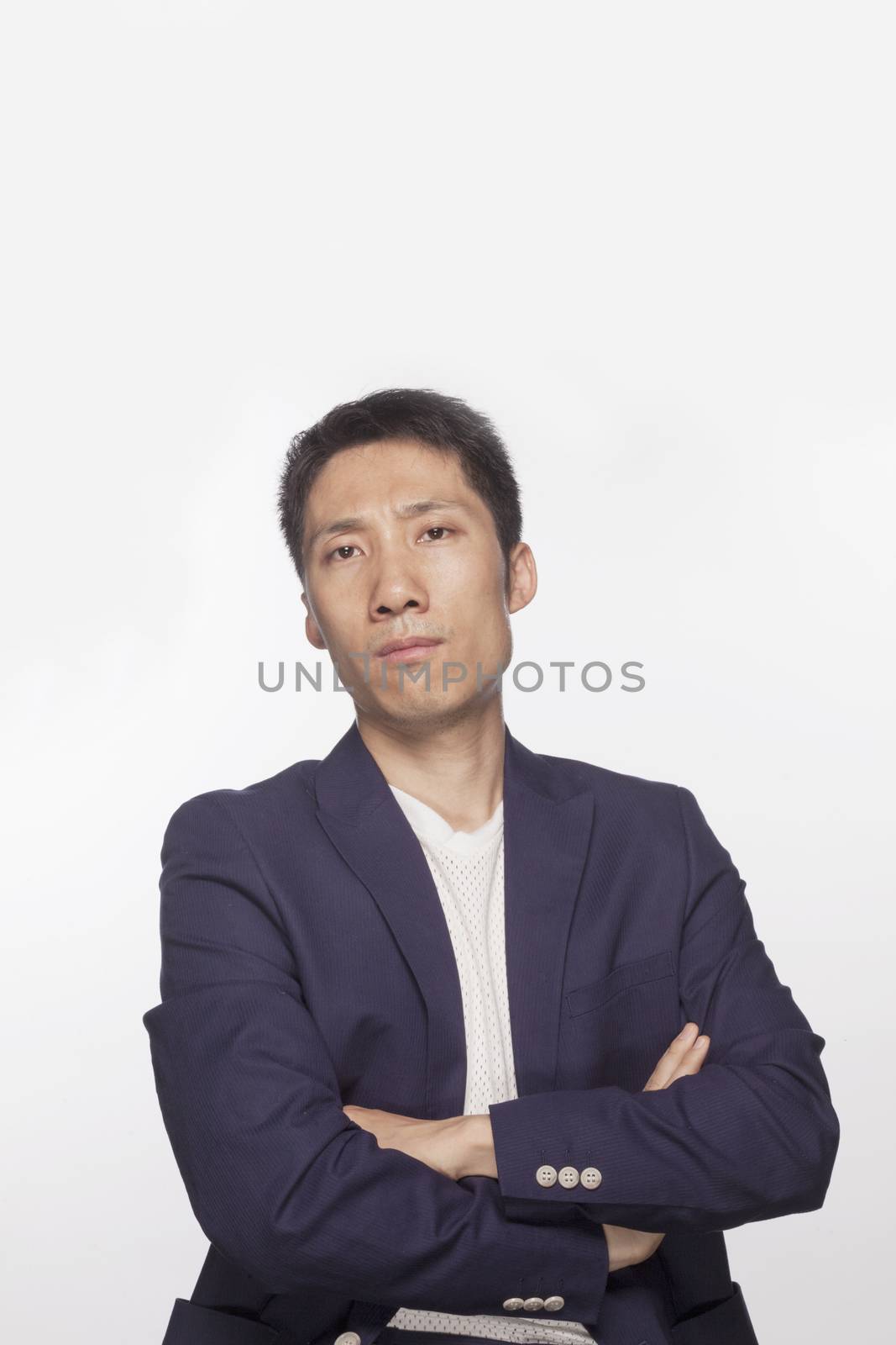 Portrait of serious man with arms crossed looking at camera, studio shot