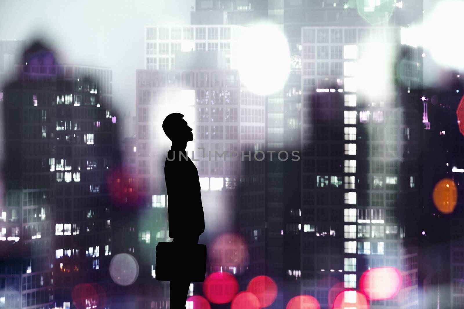 Silhouette of businessman holding a briefcase with a city at night time in the background