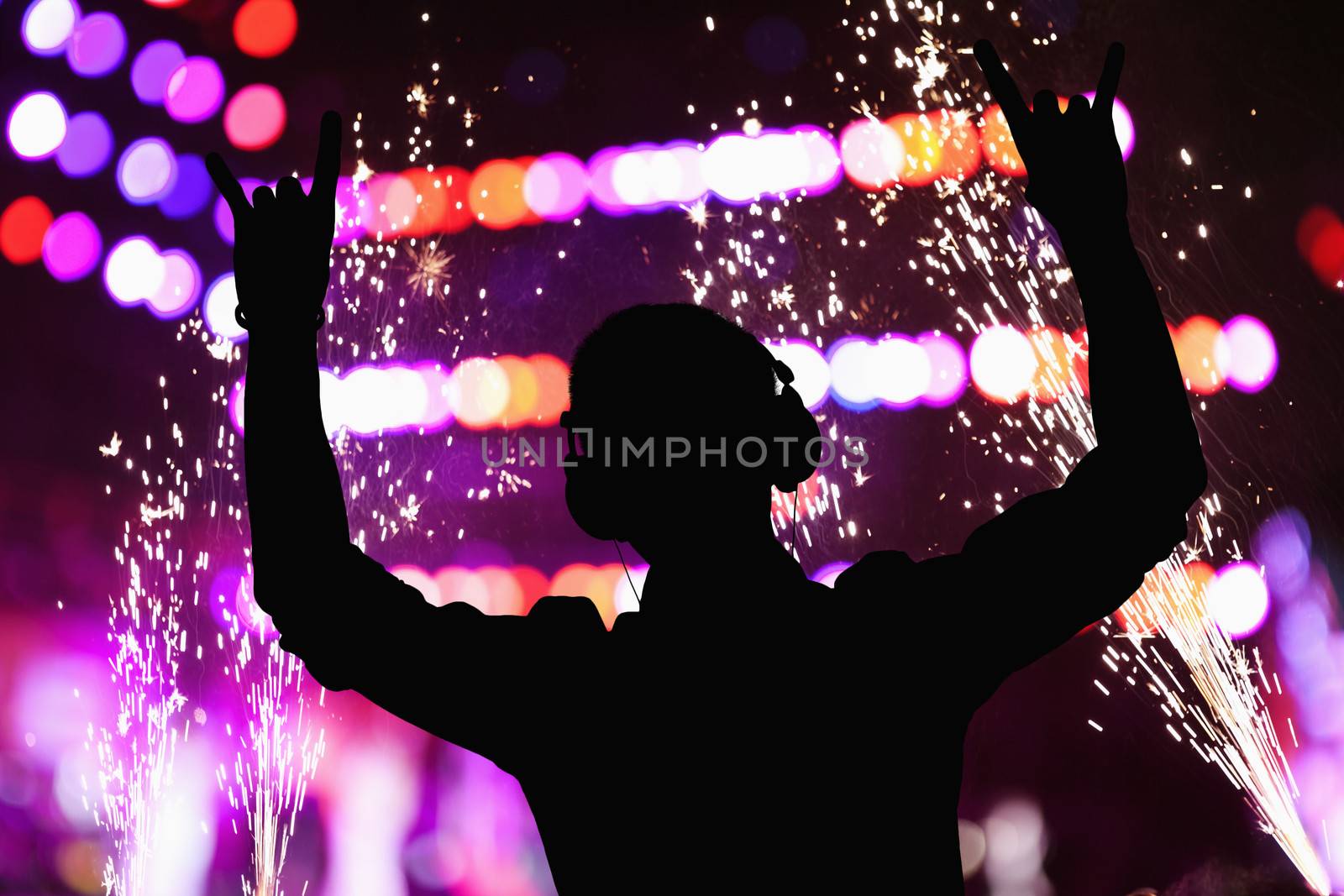 Silhouette of DJ wearing headphones and performing at a night club 