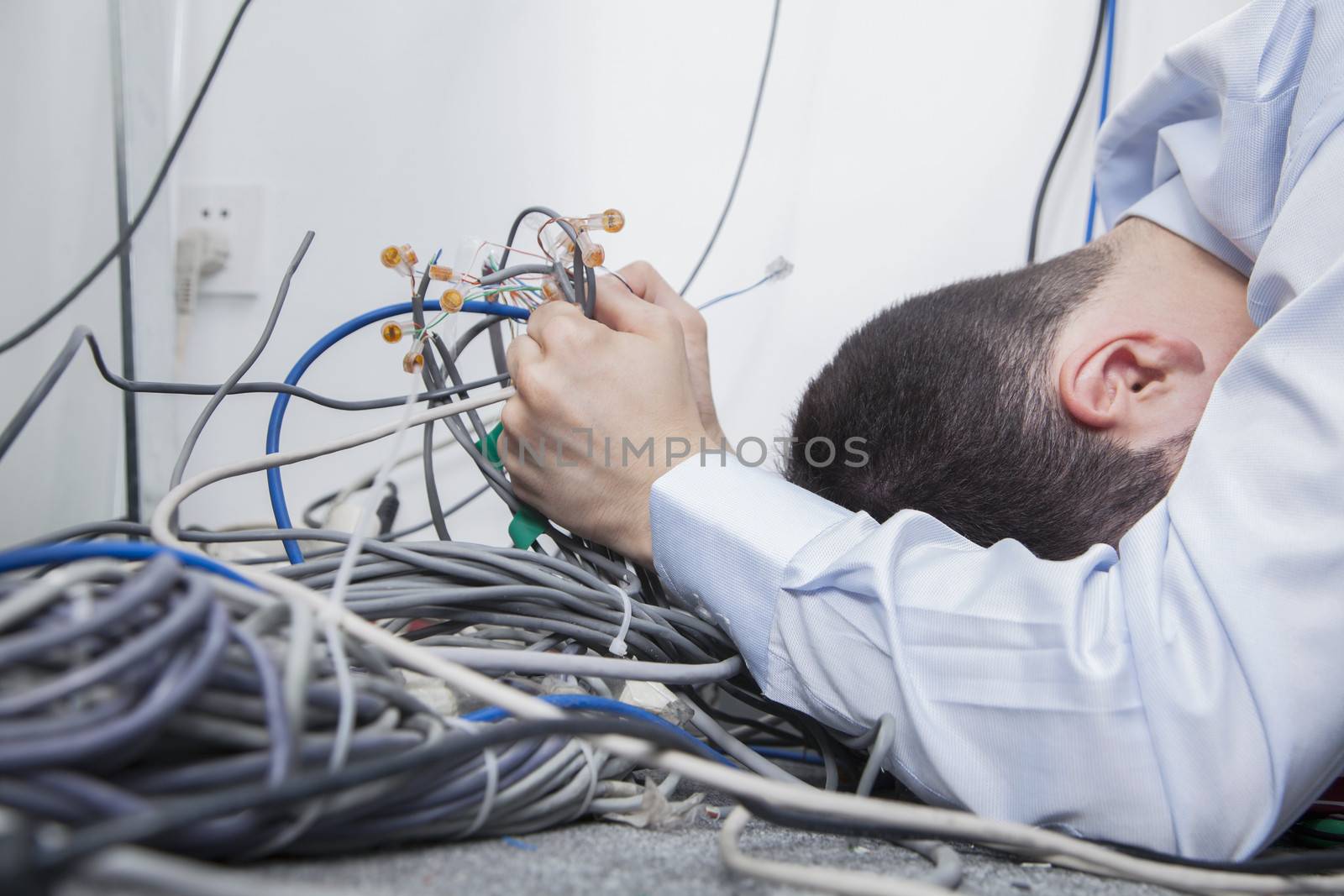Frustrated man lying down trying to figure out and sort  computer cables