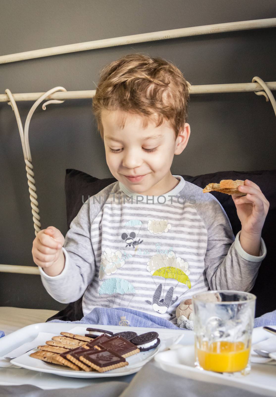 Happy child having breakfast in bed at home in the morning