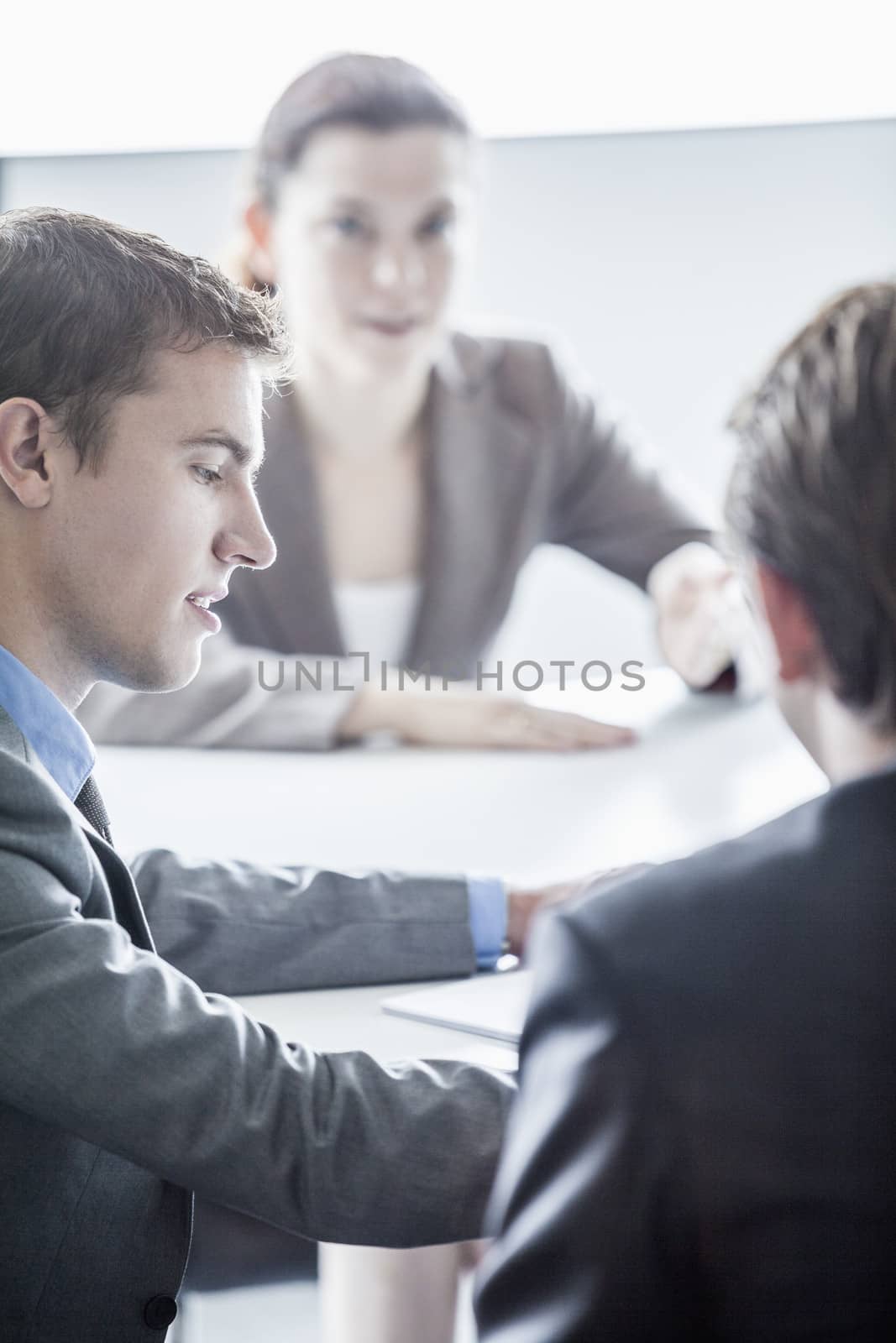 Three business people sitting at a table and having a business meeting in the office by XiXinXing