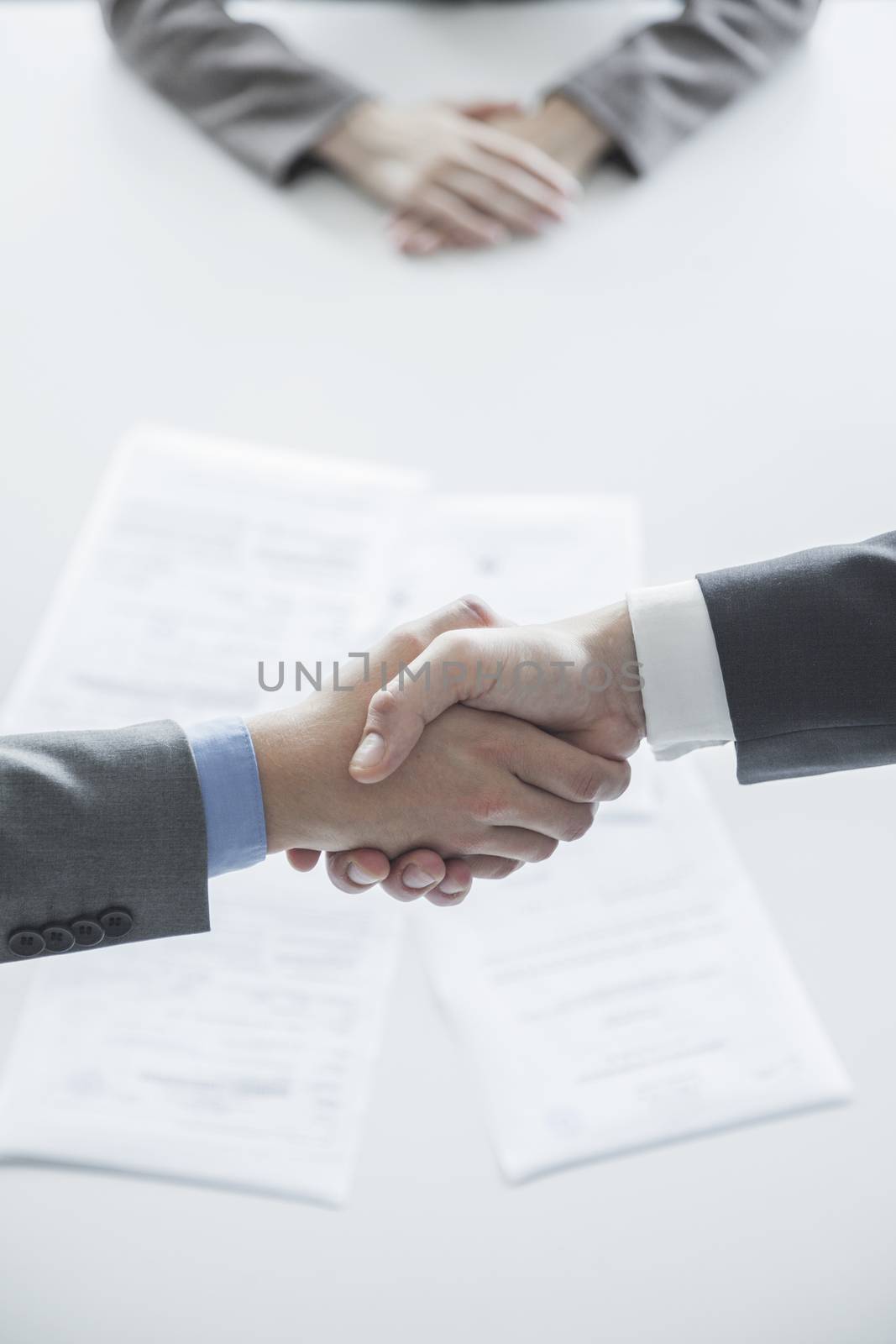 Two business people shaking hands over the table, hands only