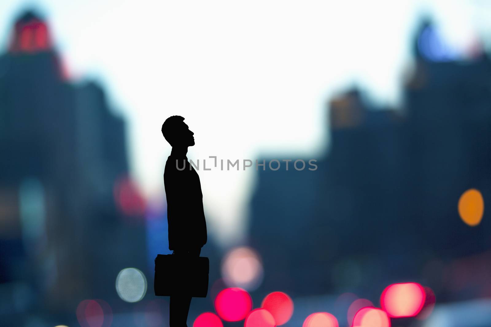Silhouette of businessman holding a briefcase with blurred city lights behind him by XiXinXing