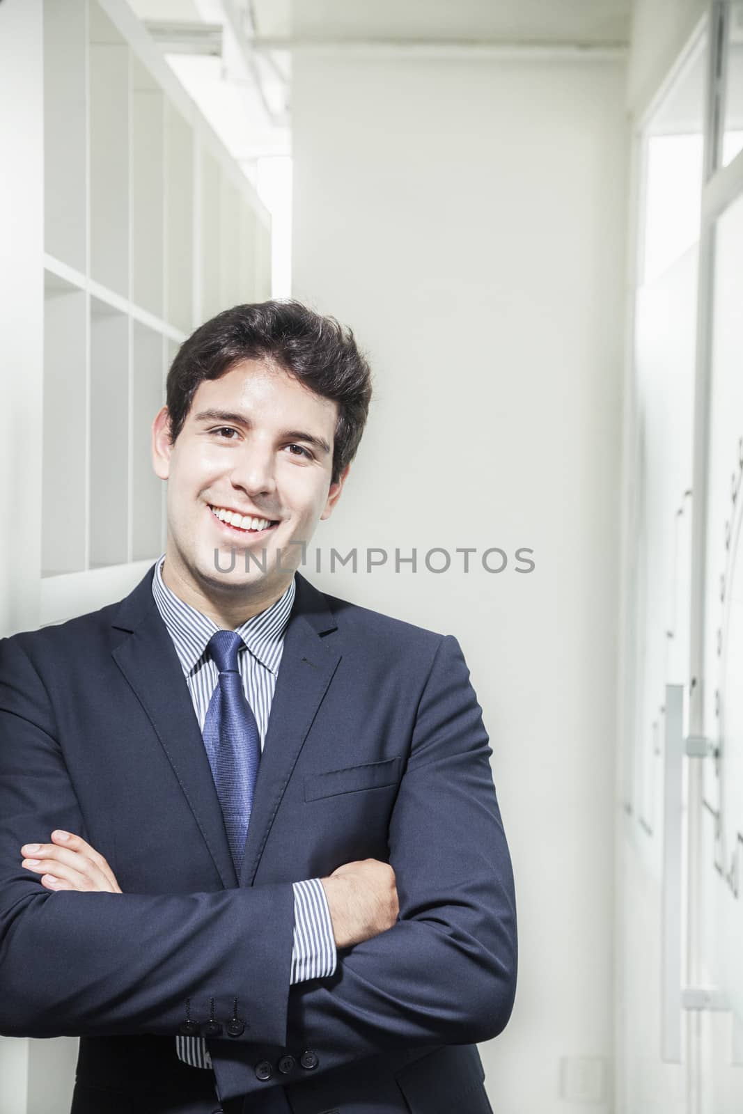 Portrait of young smiling businessman with arms crossed and looking into the camera by XiXinXing