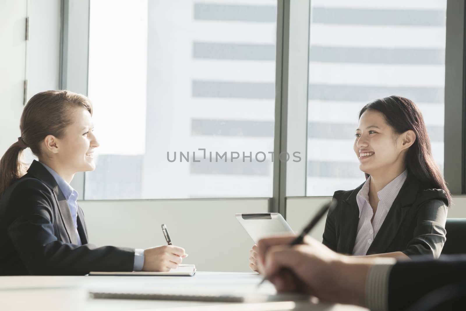Two businesswomen smiling and looking at each other during a business meeting