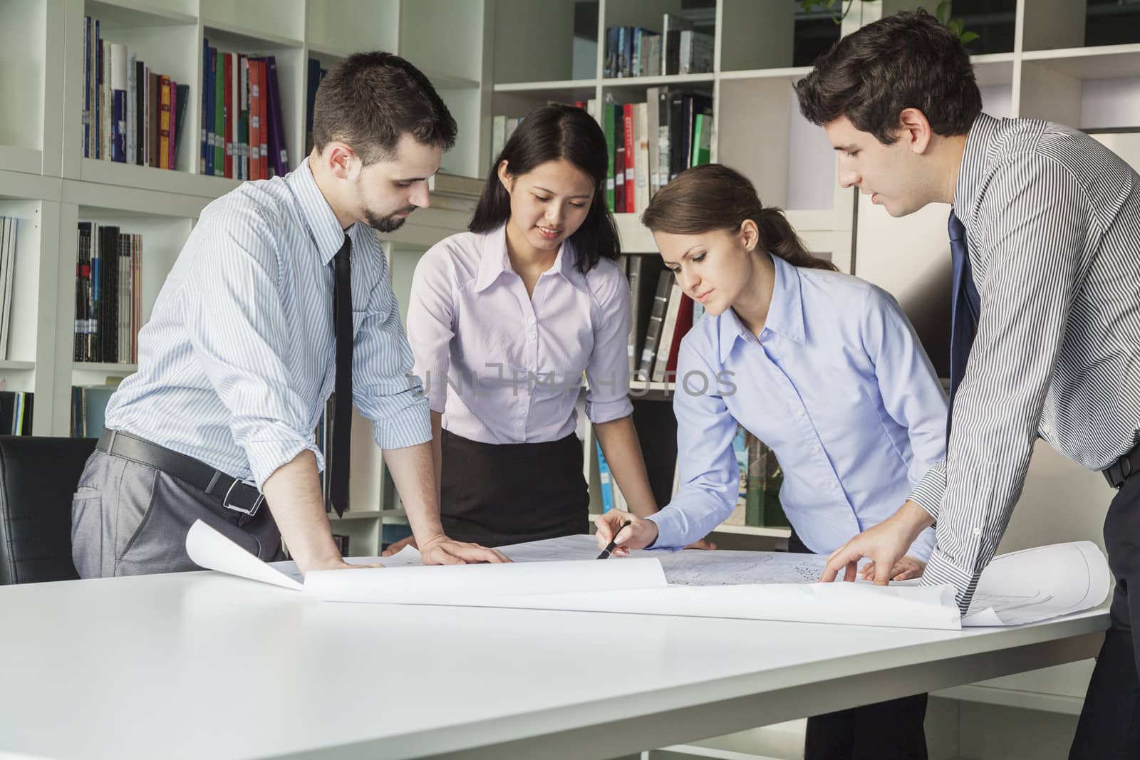 Four architects standing and planning around a table while looking down at blueprint by XiXinXing