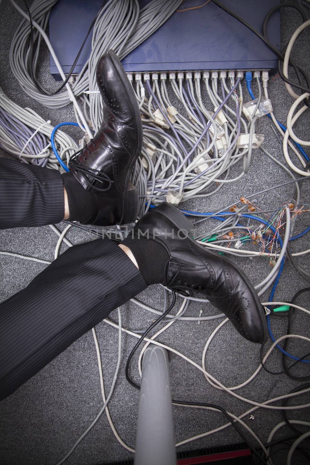 Businessman's feet on the ground surrounded by computer cables