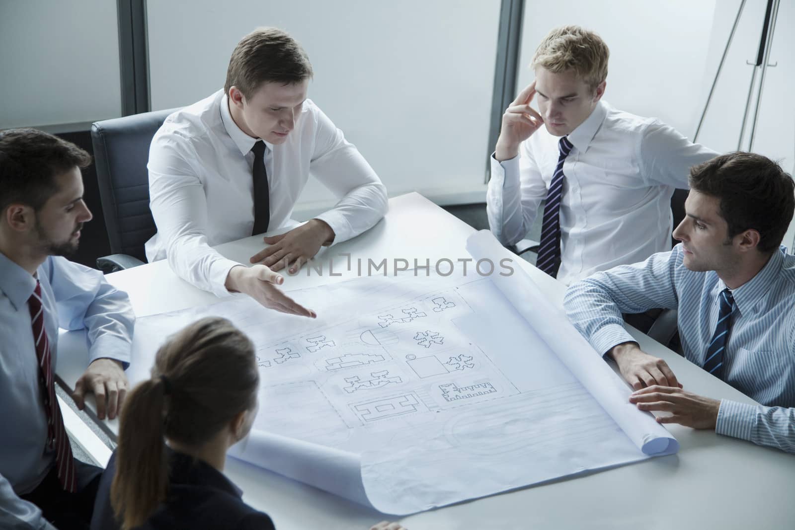 Five architects discussing and planning over a blueprint in the office