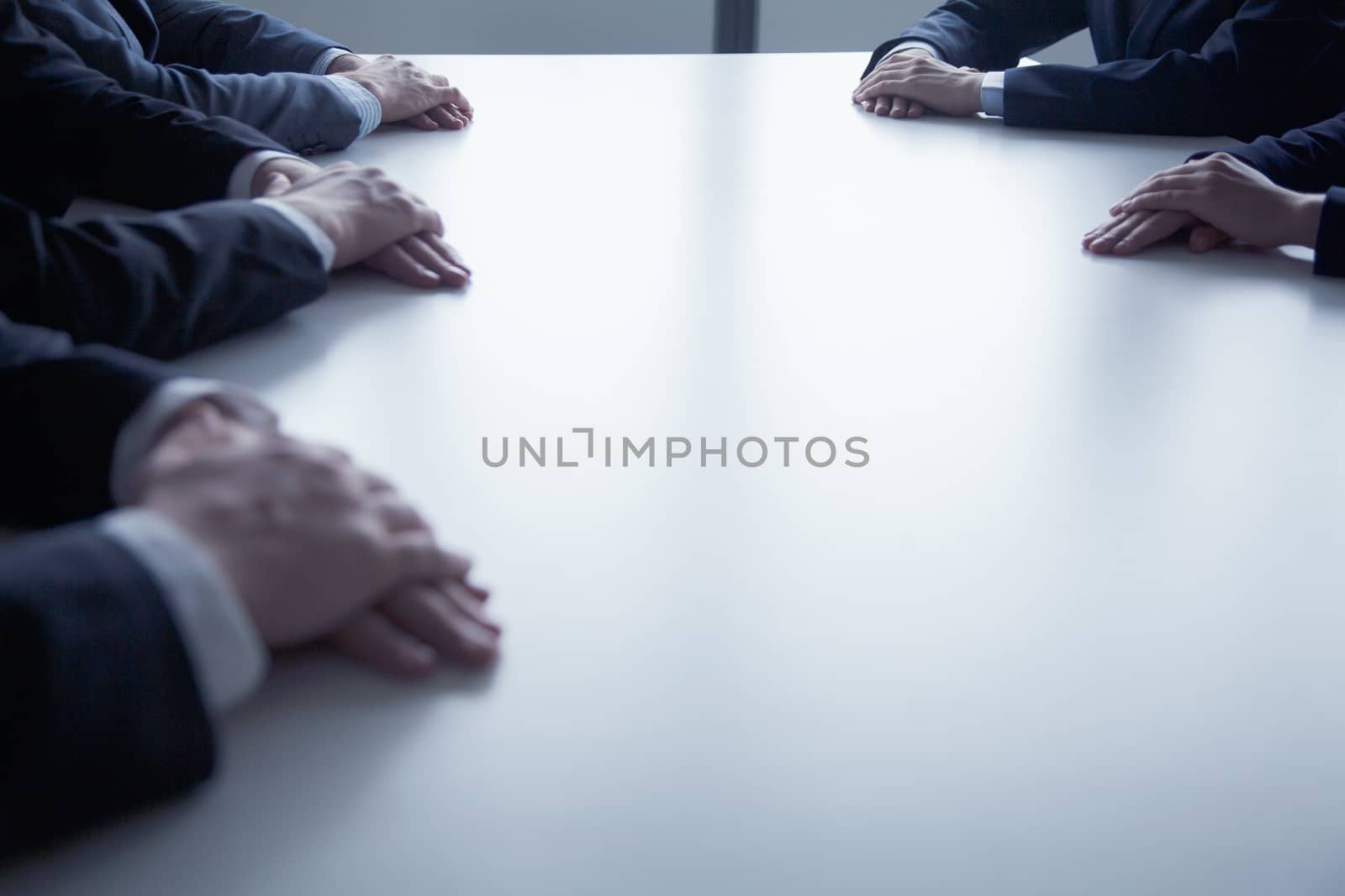 Close-up on folded hands of business people at the table during a business meeting