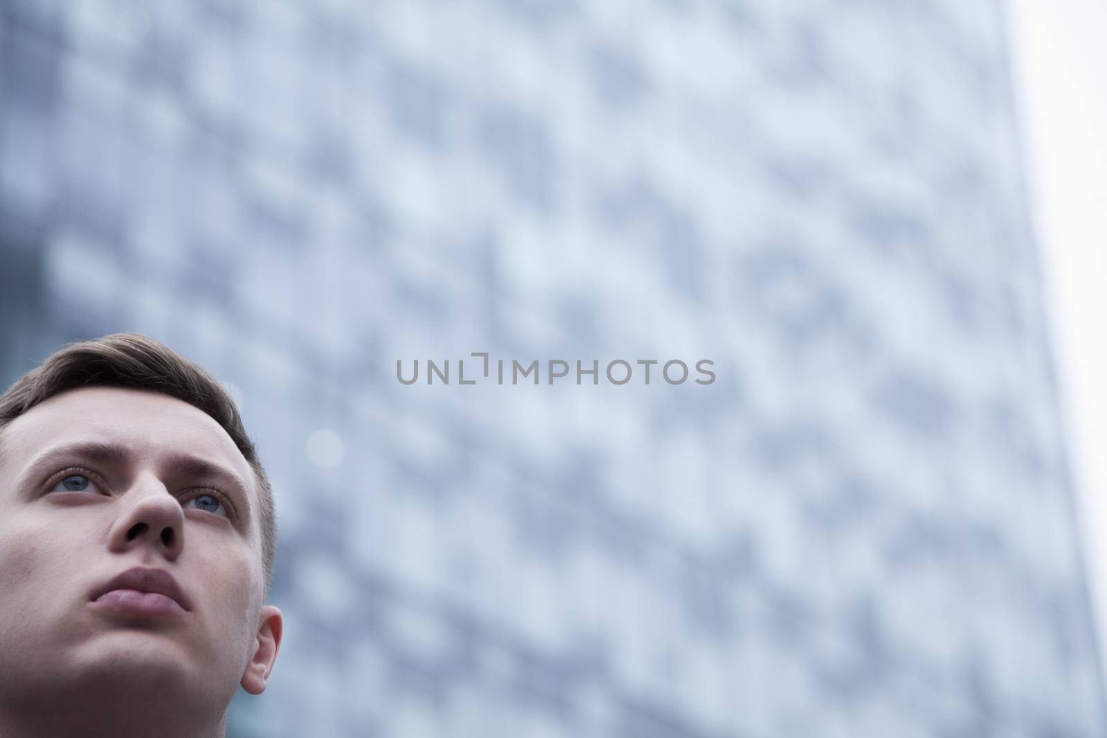 Portrait of serious young businessman looking up, outdoors, business district