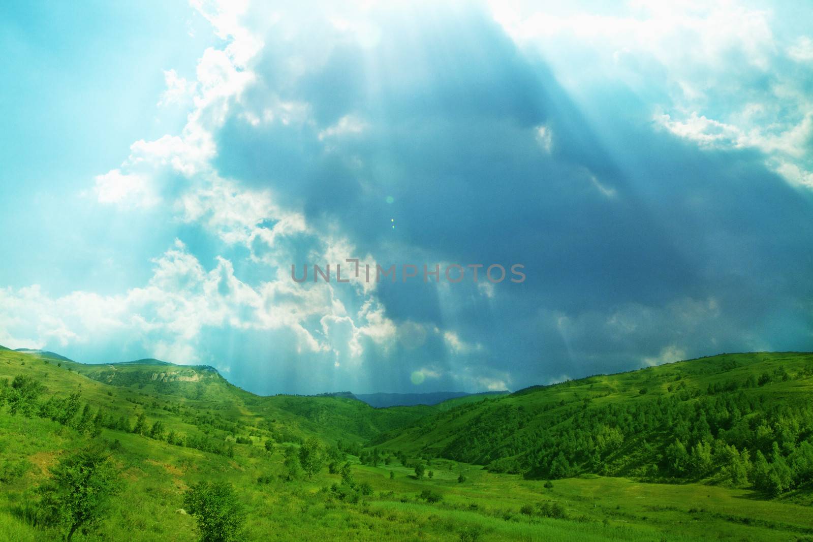 Lush, green landscape with sun shining through clouds. by XiXinXing