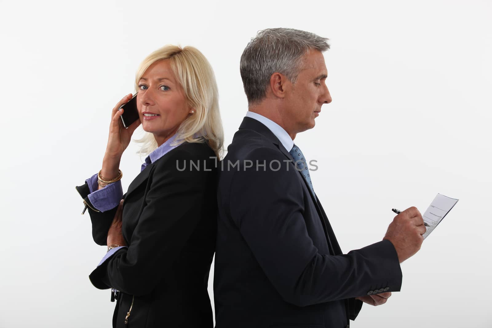 mature businessman and female partner standing back to back by phovoir
