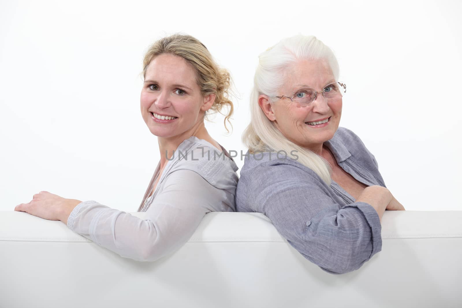 Mother and daughter sitting on white sofa by phovoir