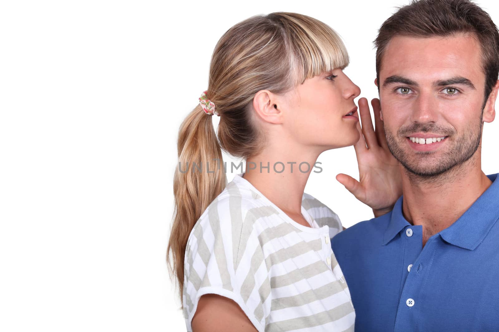 Young woman whispering into her boyfriend's ear by phovoir