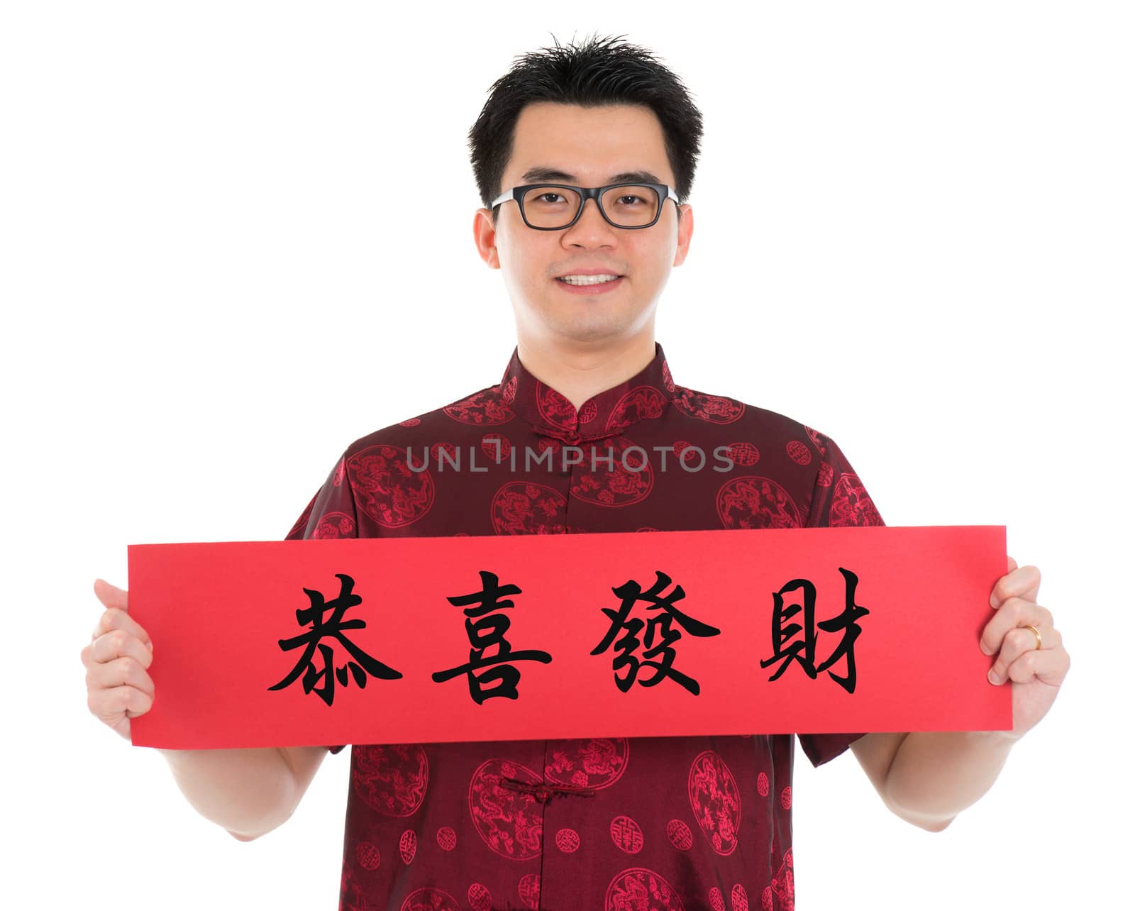Asian man with Chinese traditional cheongsam or tang suit holding couplet, the Chinese word means congratulations and best wishes for a prosperous New Year.  Male model isolated on white background.