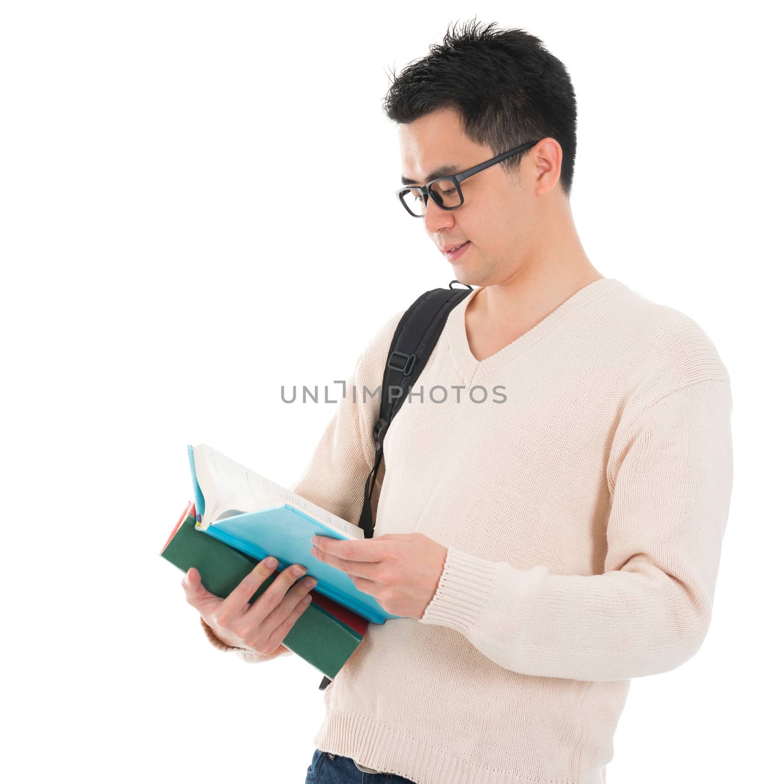 Asian adult student in casual wear with school bag carrying text books reading book standing isolated on white background. Asian male model.