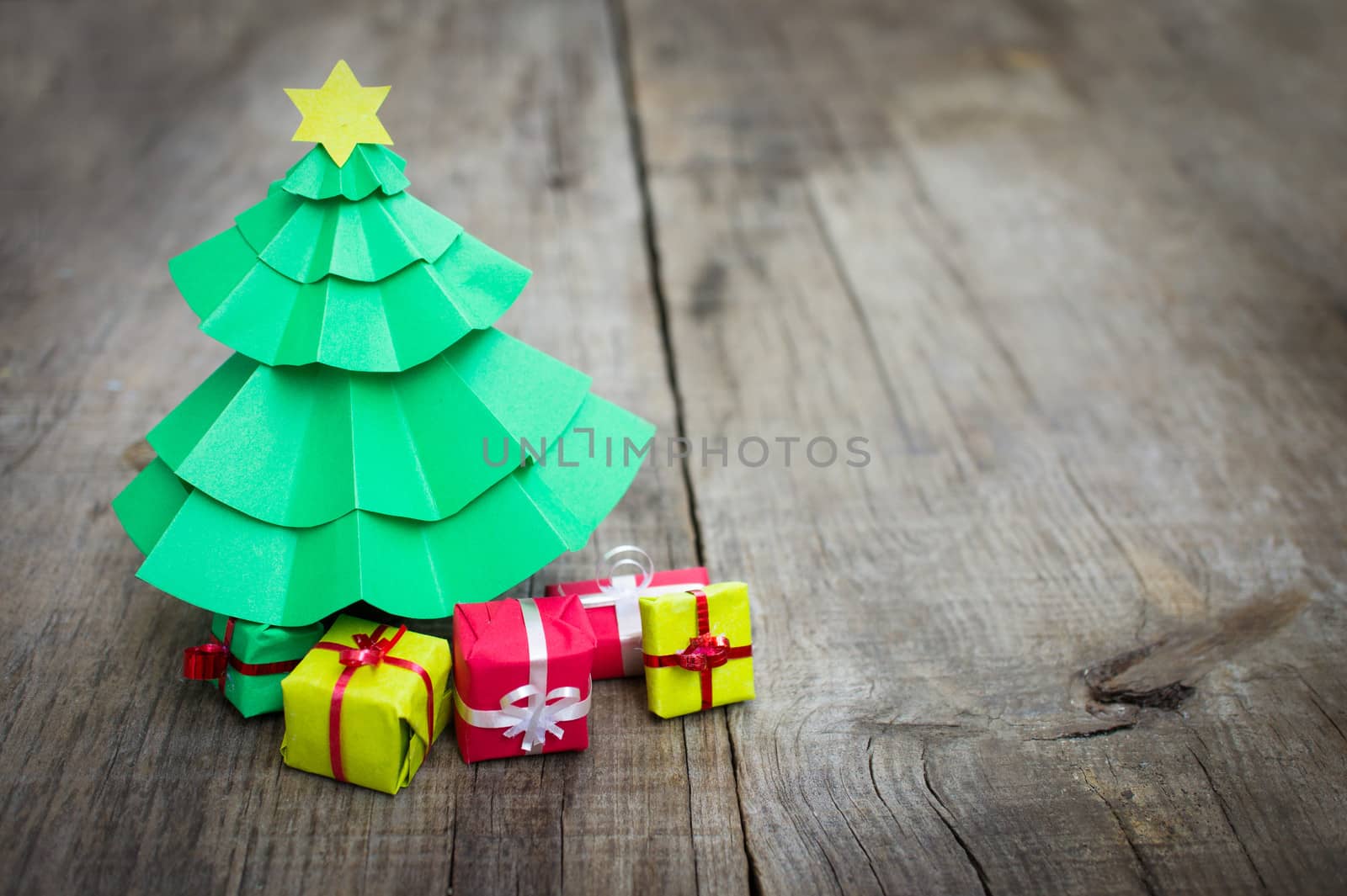 Paper miniature christmas tree with present on wood background