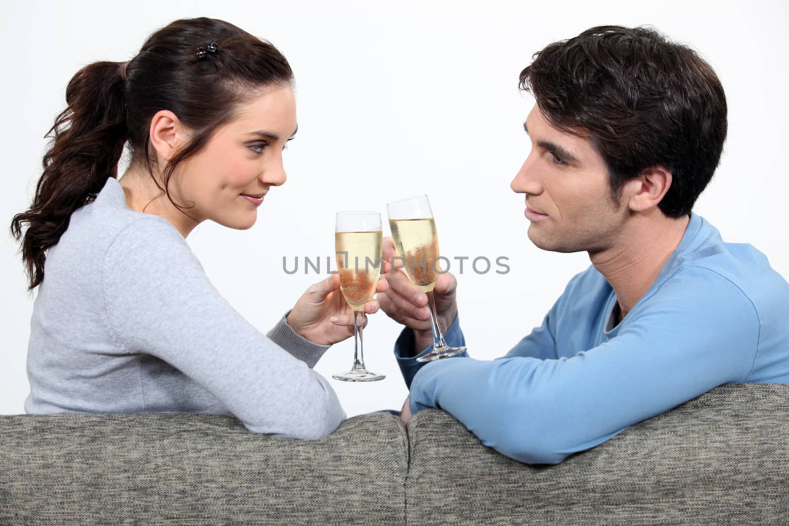 Couple drinking champagne on sofa by phovoir
