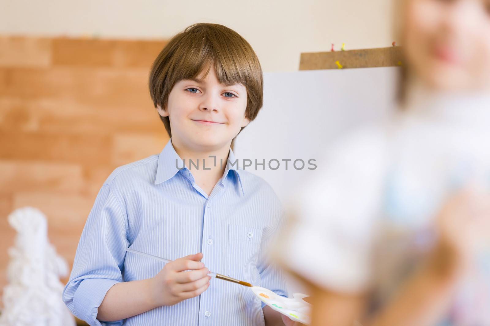 Image of little cute boy painting pictures at kindergarten