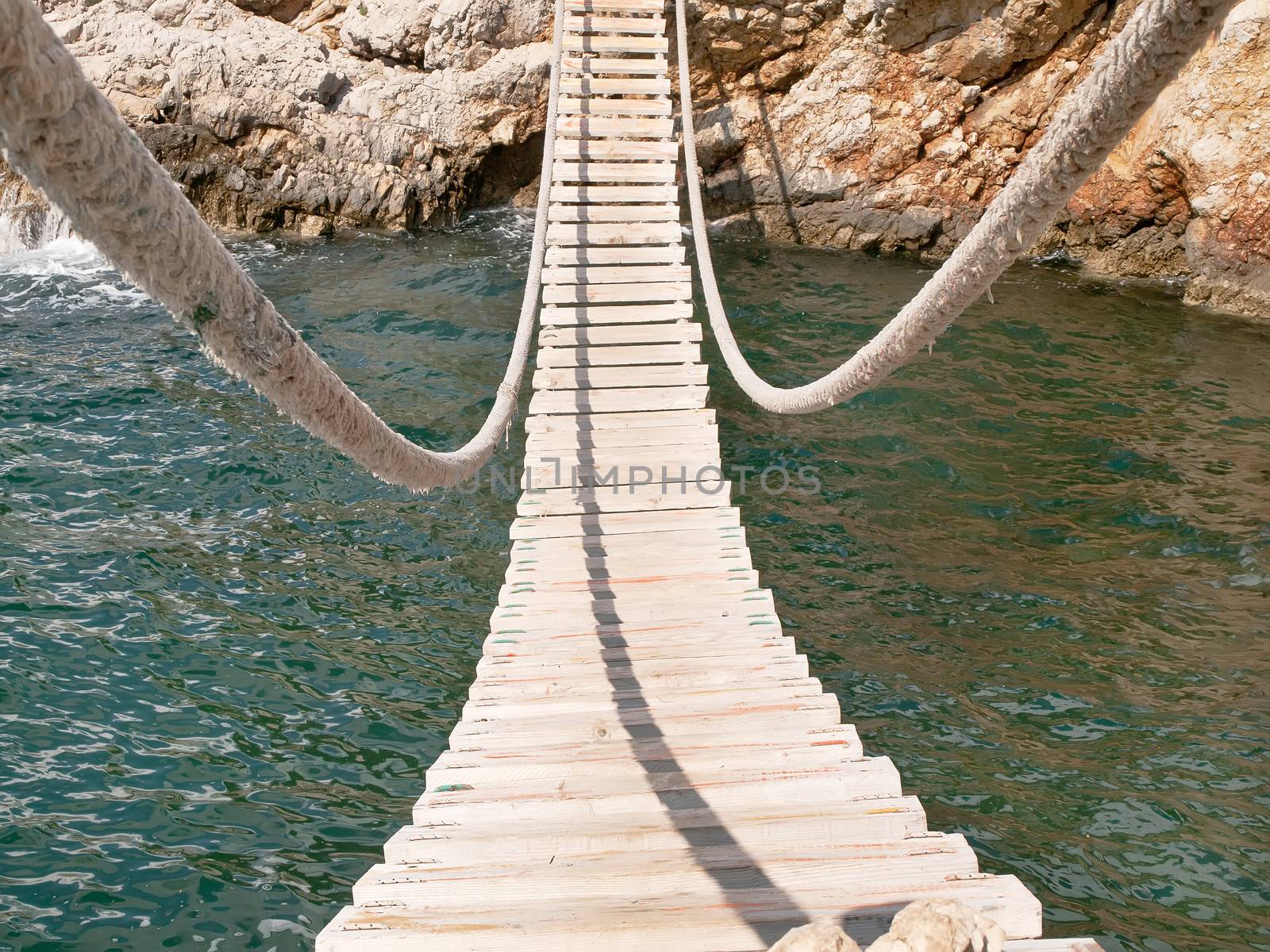 hanging wooden bridge connect rocky seacost