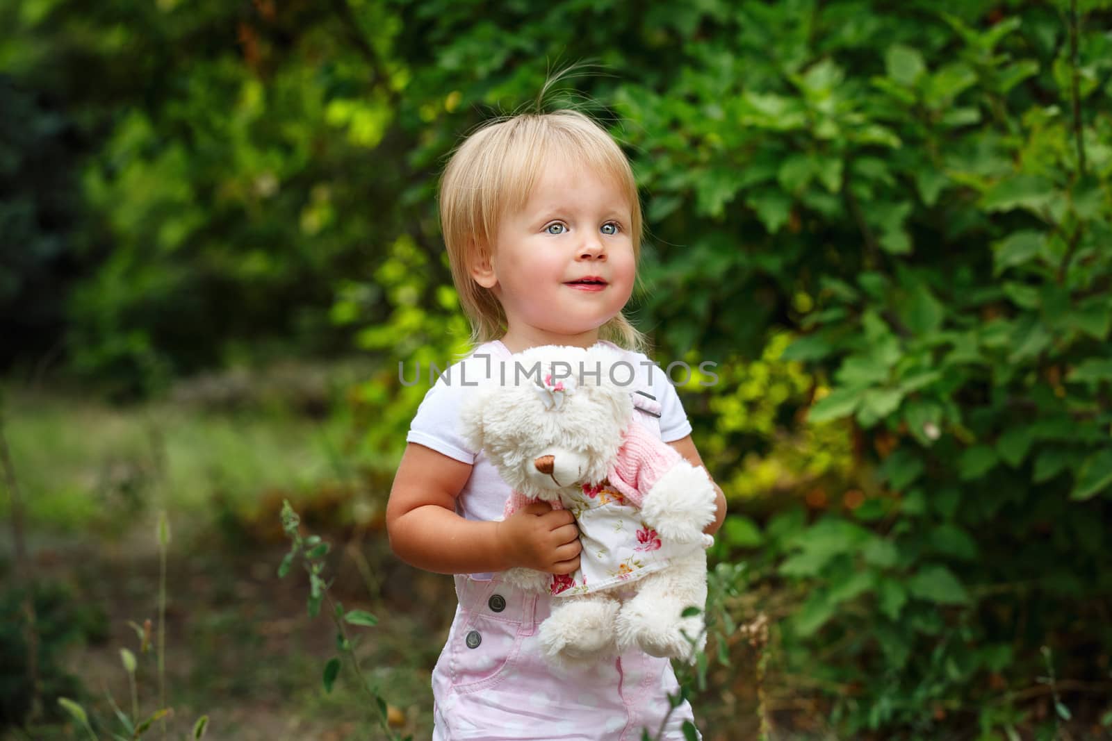 Blond girl with blue eyes holding a teddy bear