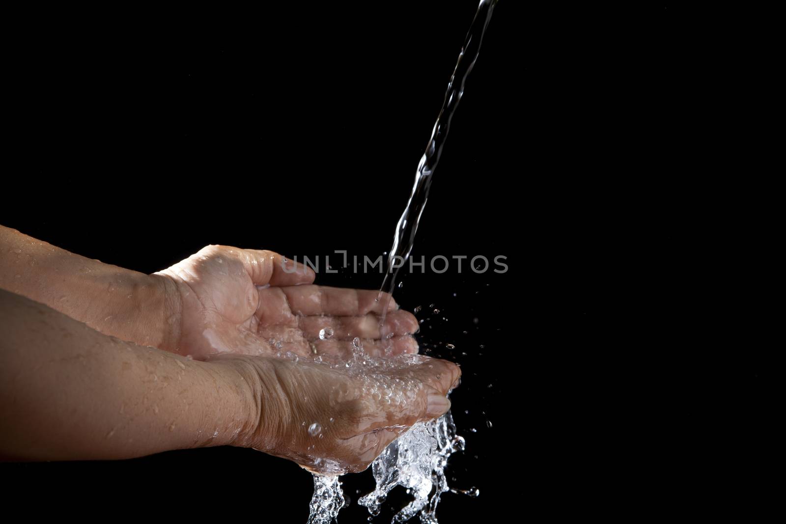hand and pouring water on black background by khunaspix