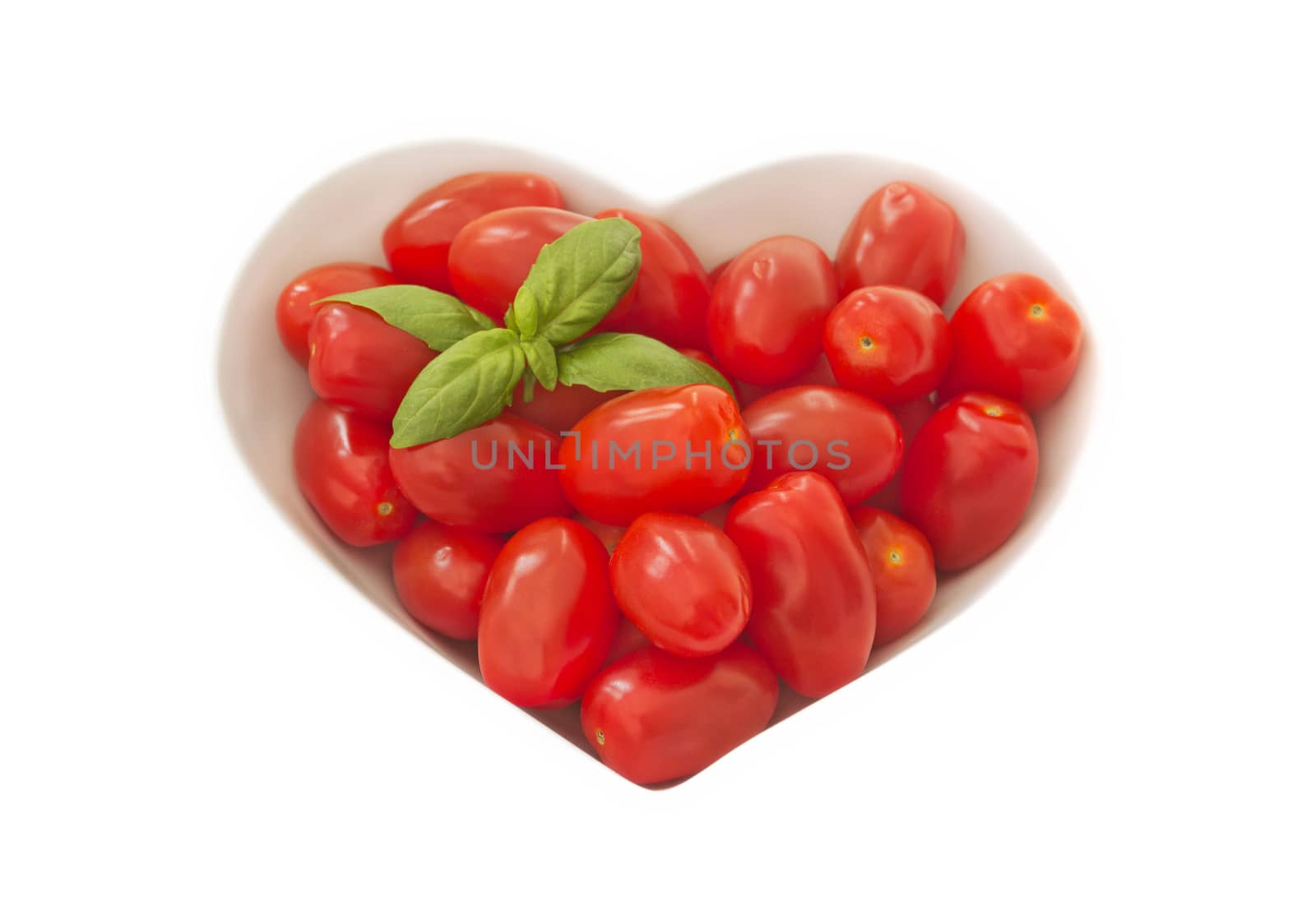 A bowl of baby plum tomatoes on a light coloured cloth. there is a sprig of basil in the top left hand corner to give a splash of green.