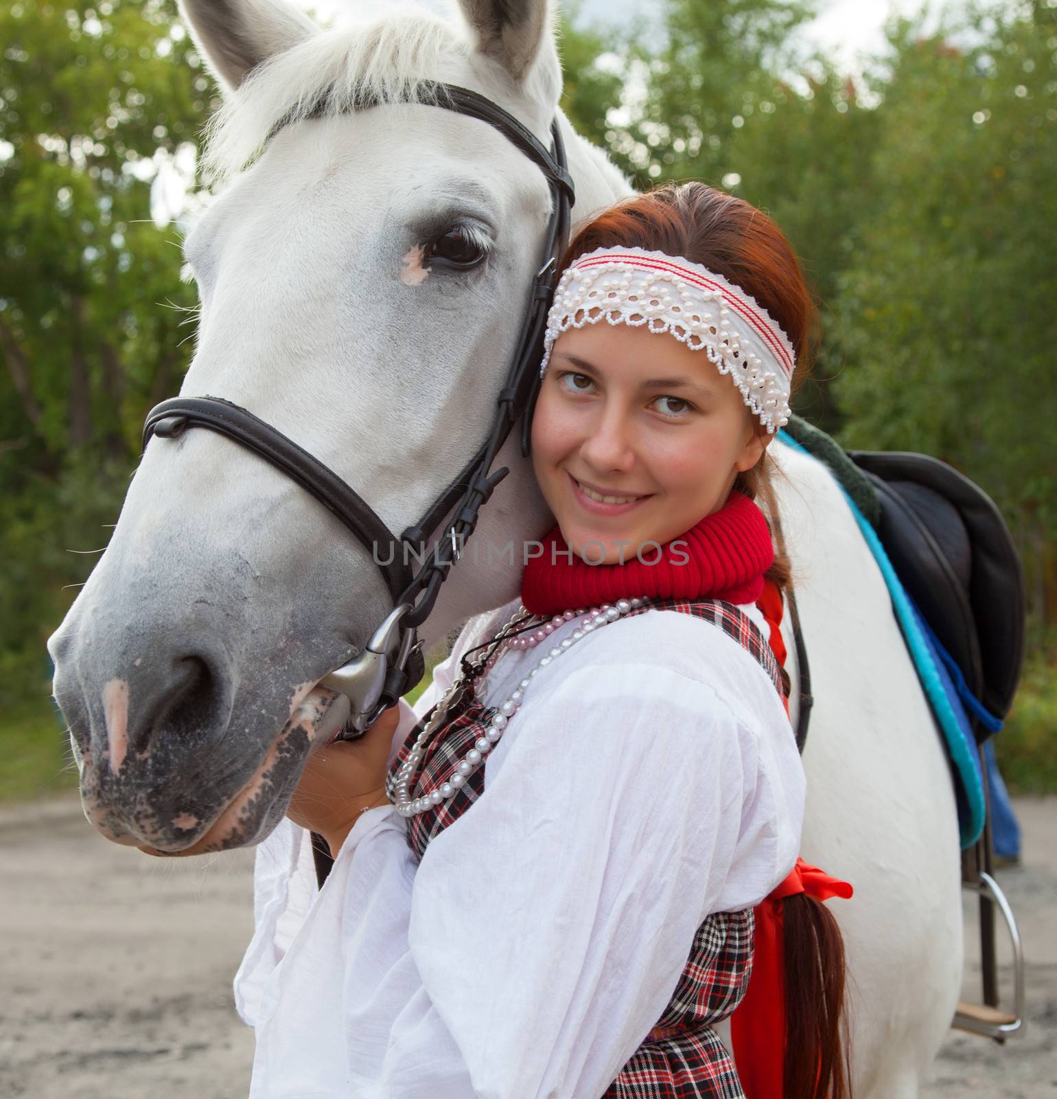 Portrait of a girl in traditional Russian costume next to a horse