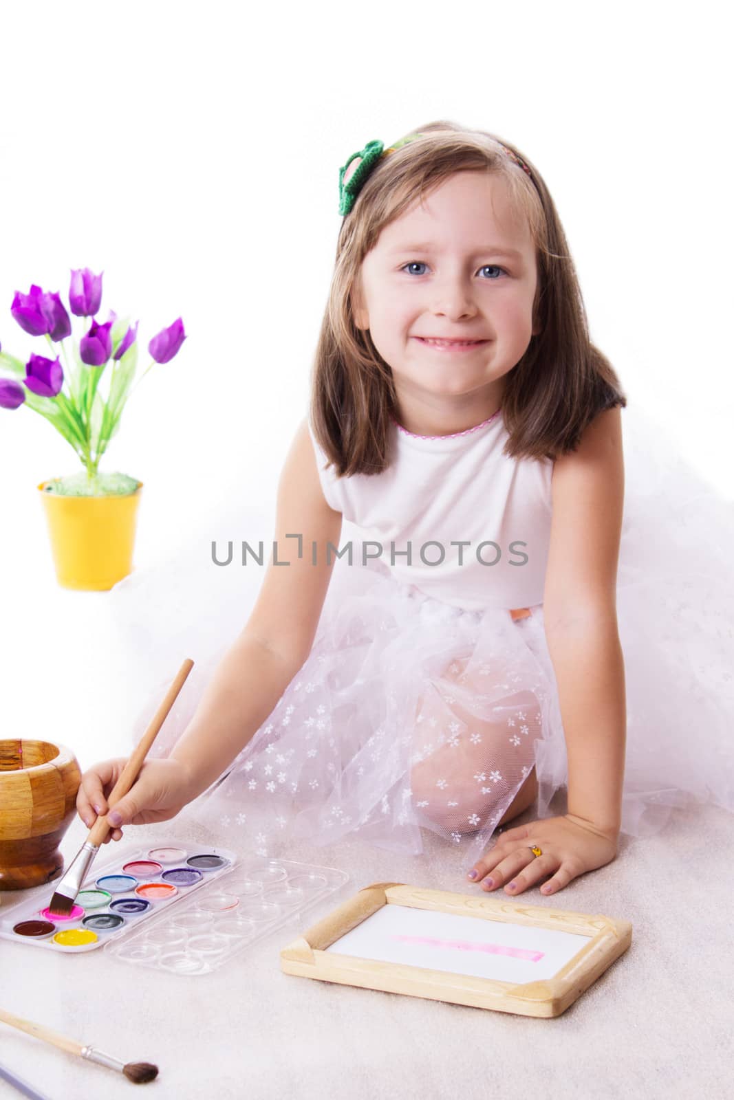 Happy five year girl drawing with paint isolated on white
