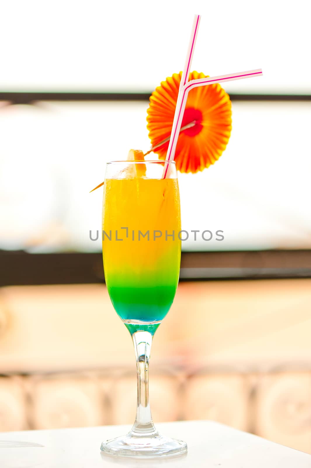 bright alcoholic cocktail in a glass with decorations on the edge of the table by kosmsos111