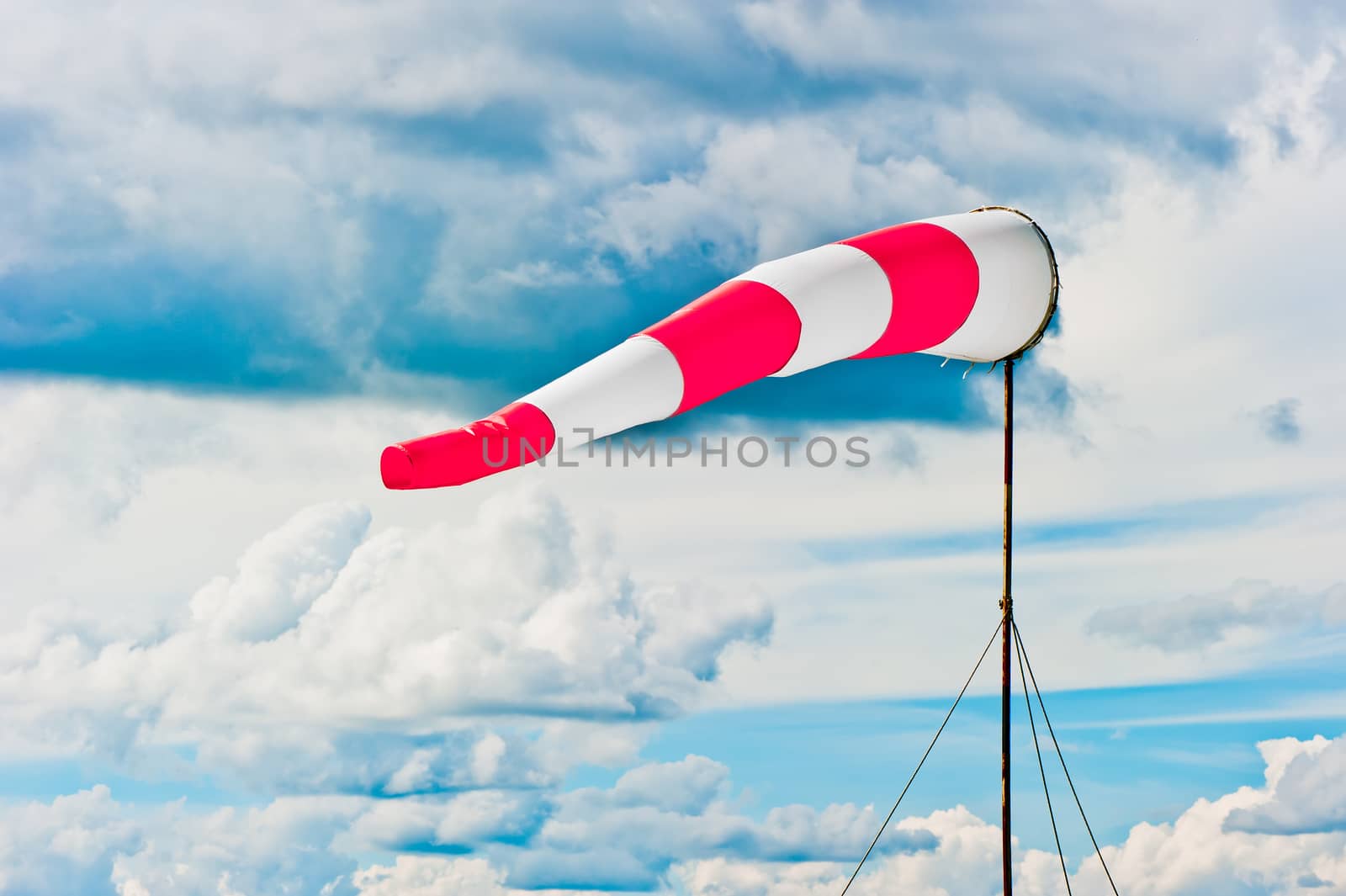 striped windsock at the airport on the background of beautiful clouds by kosmsos111