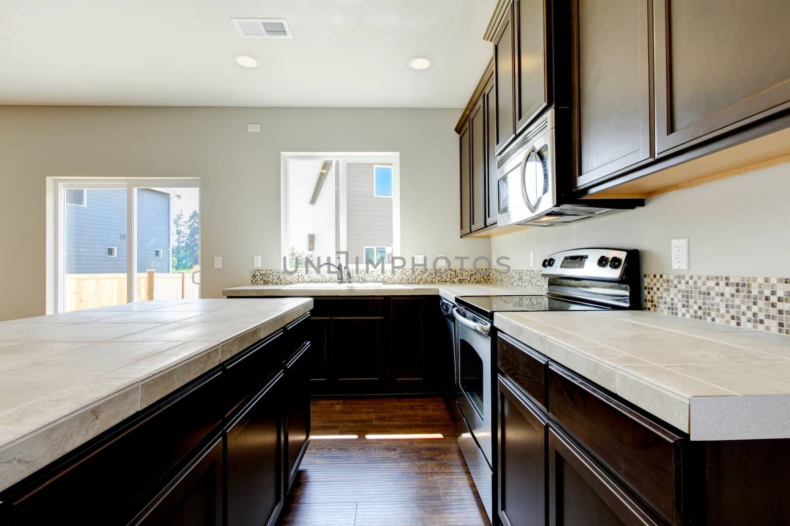 New home kitchen interior with dark brown cabinets and hardwood floors.