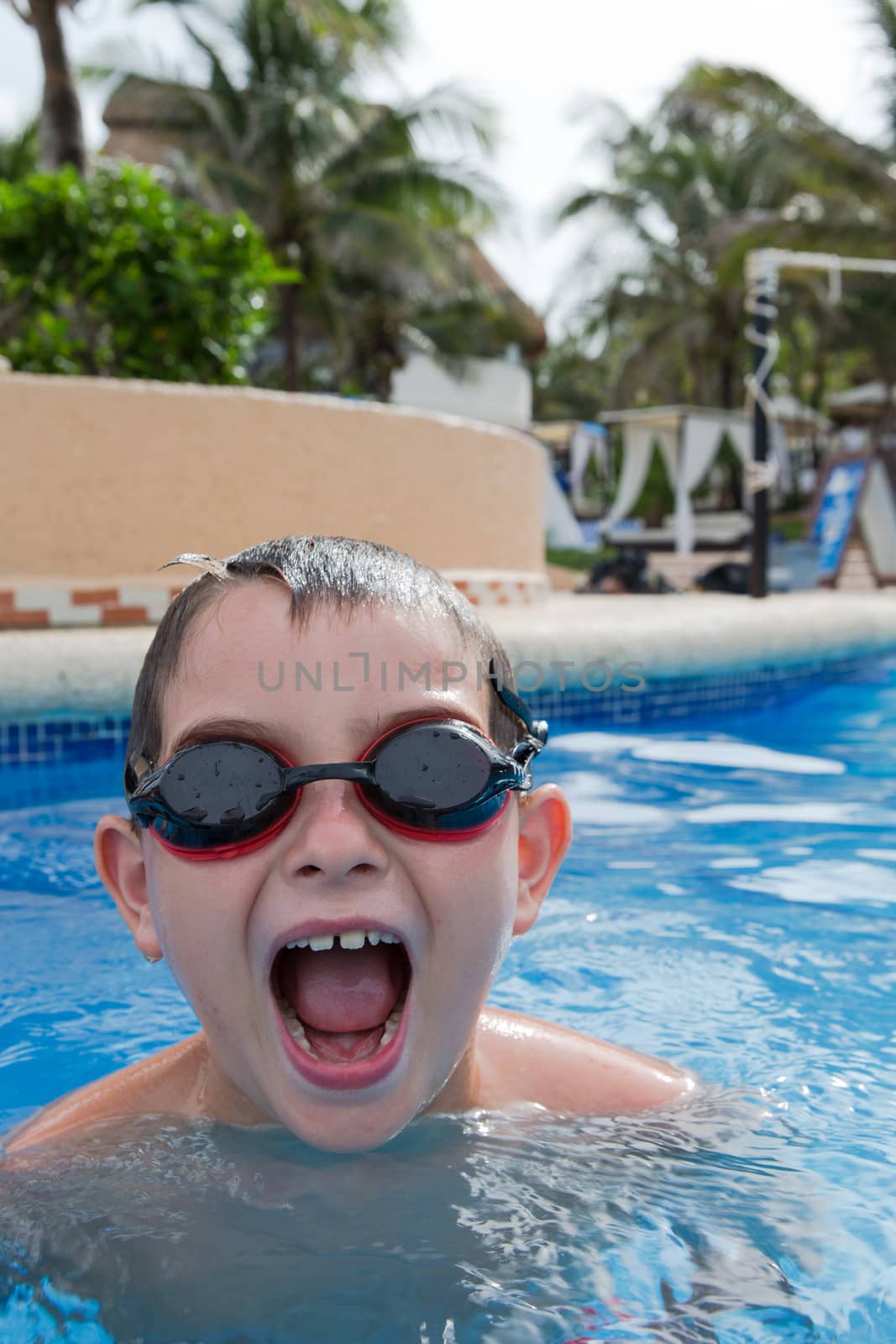 Kid having blasting fun in the swimming pool with his goggles on