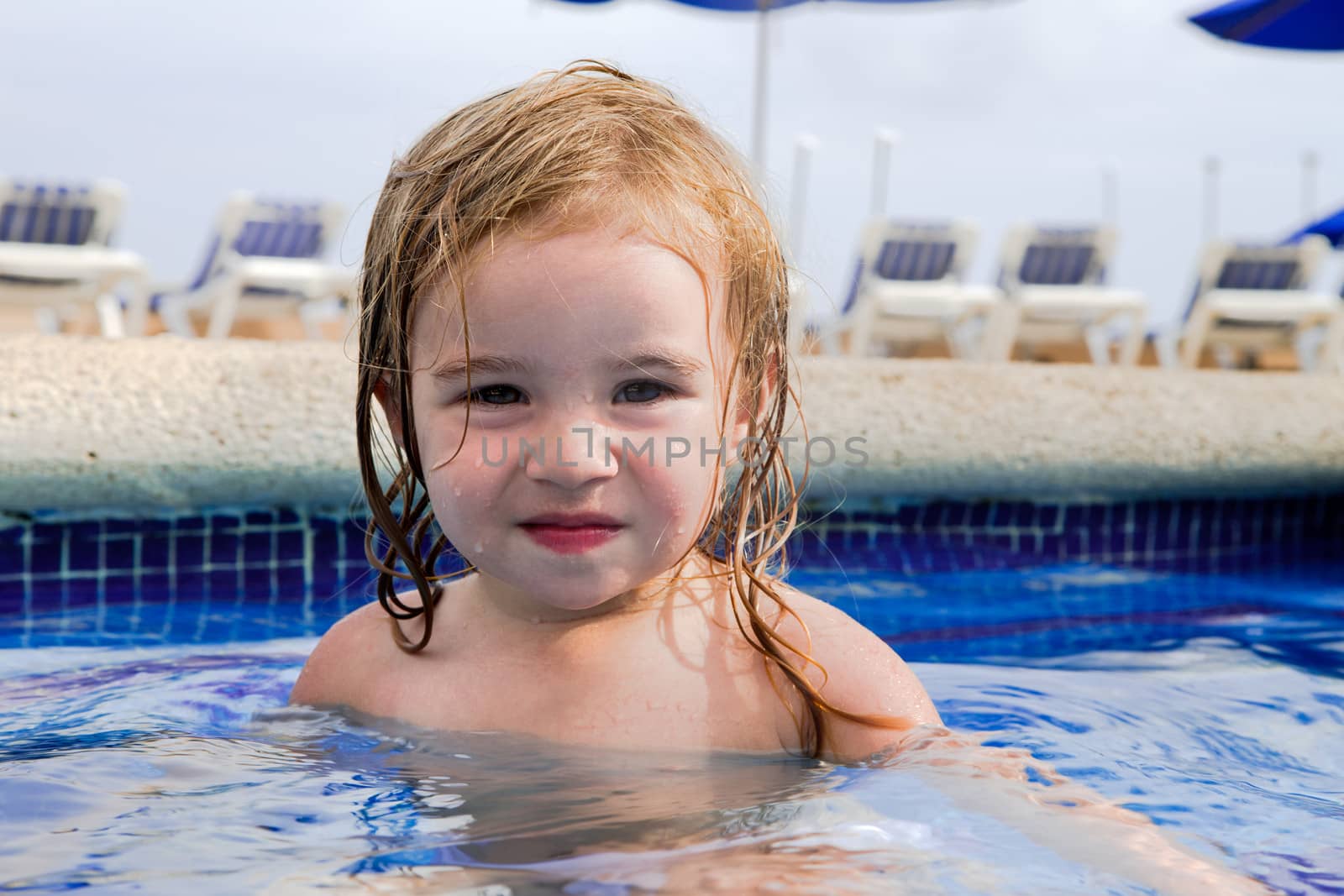 Pretty tired girl in the swimming pool looking at camera, perhaps she swimmed all day long