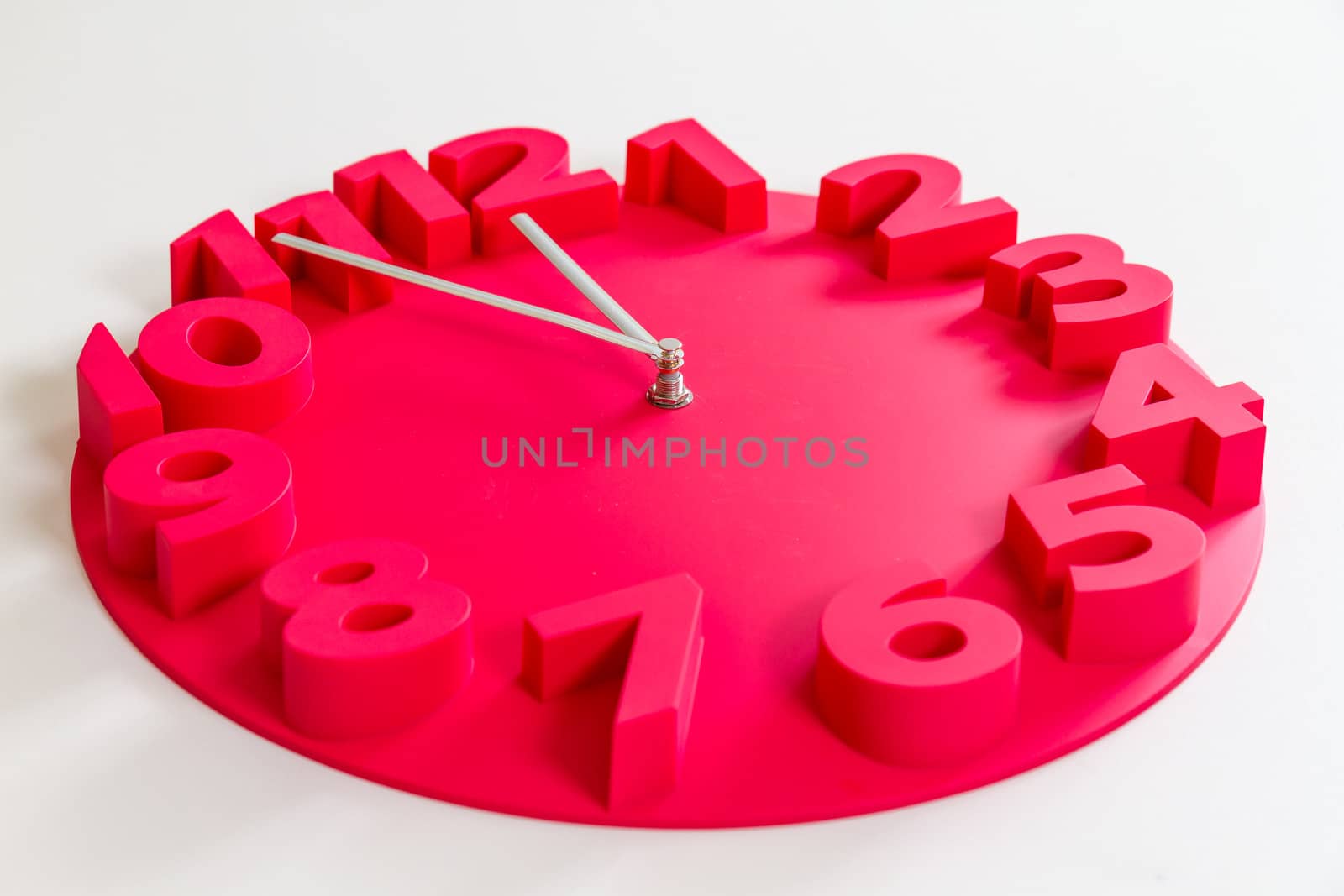 Red clock on isolated white showing five minutes to midnight