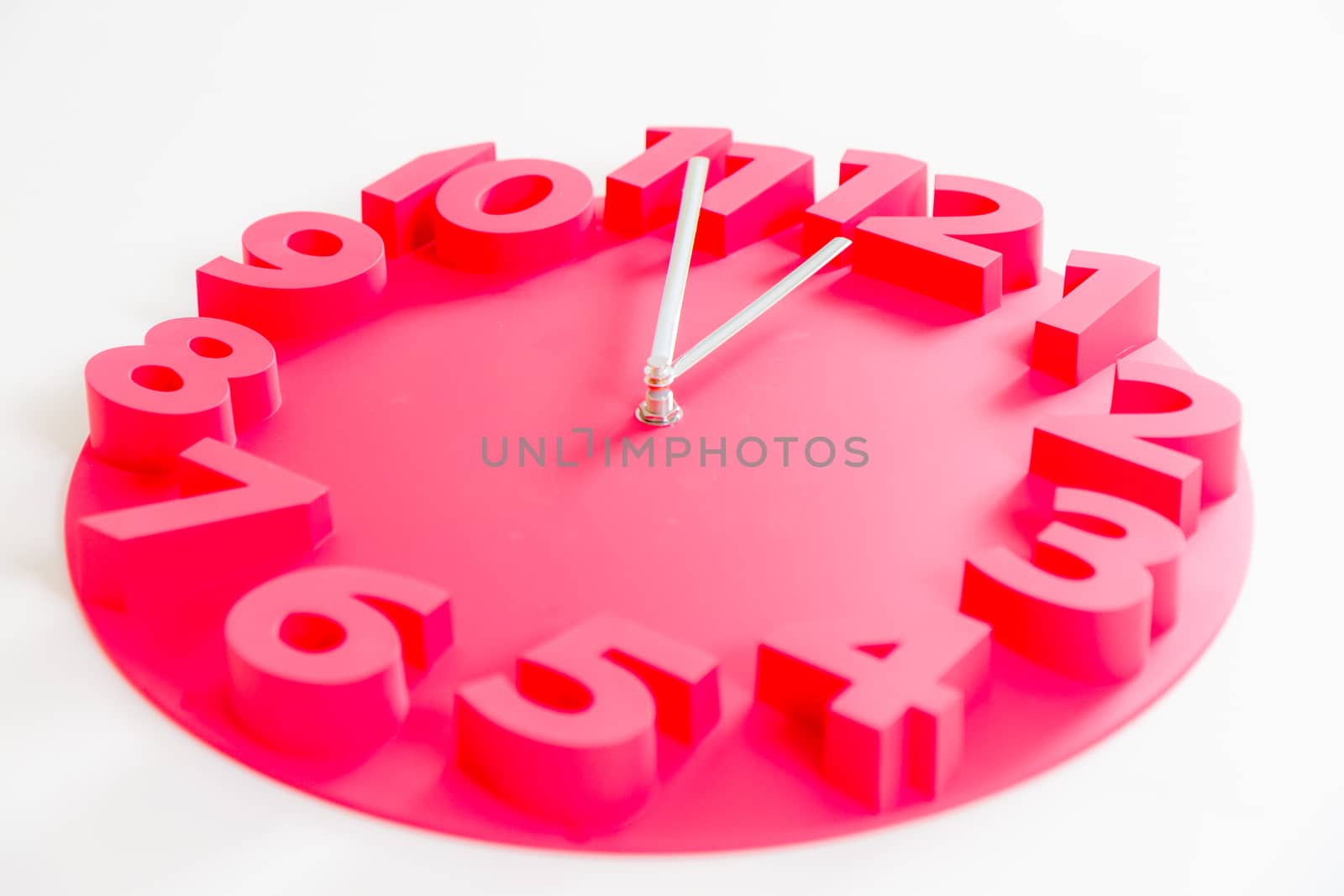 Red clock on isolated white showing five minutes to midnight