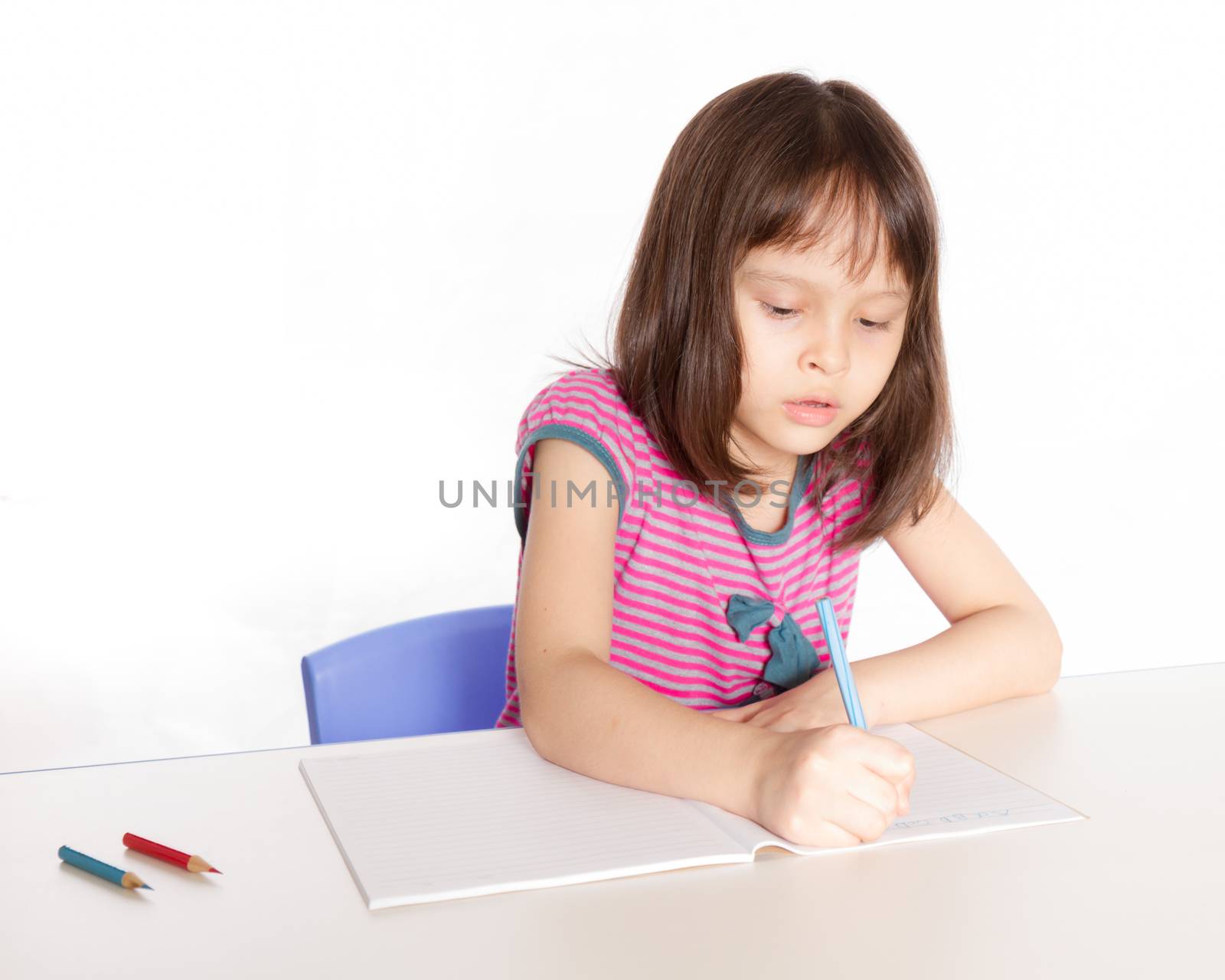 Child at desk with pencils and notebook