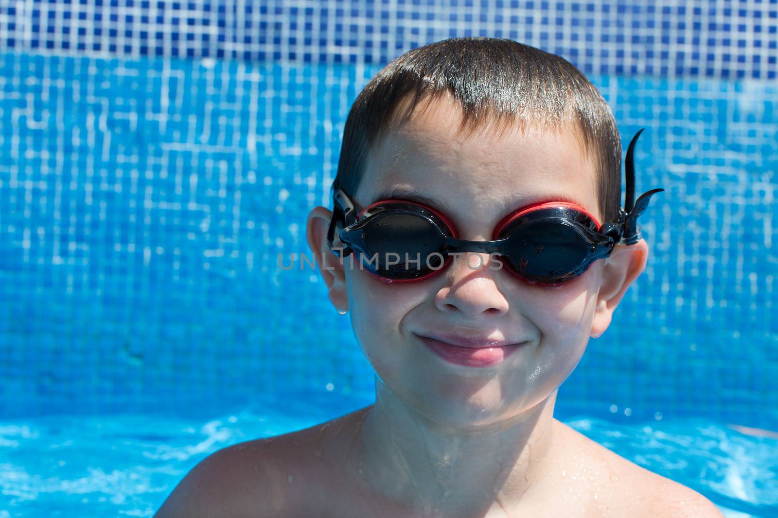 Eight years old kid in the swimming pool looking with his goggles