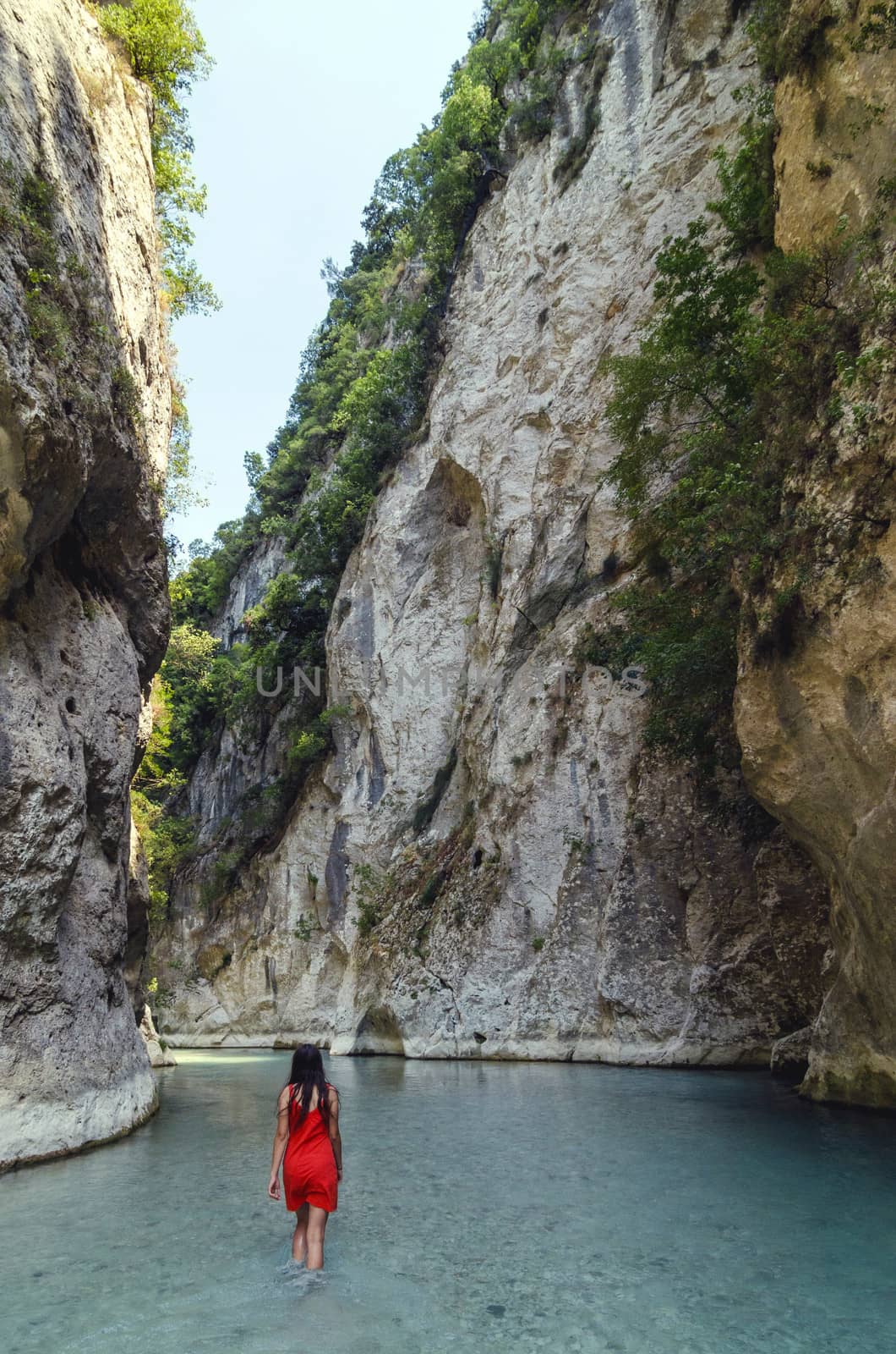 Girl in red dress exploring gorge valley, Aacheron springs, Greece.