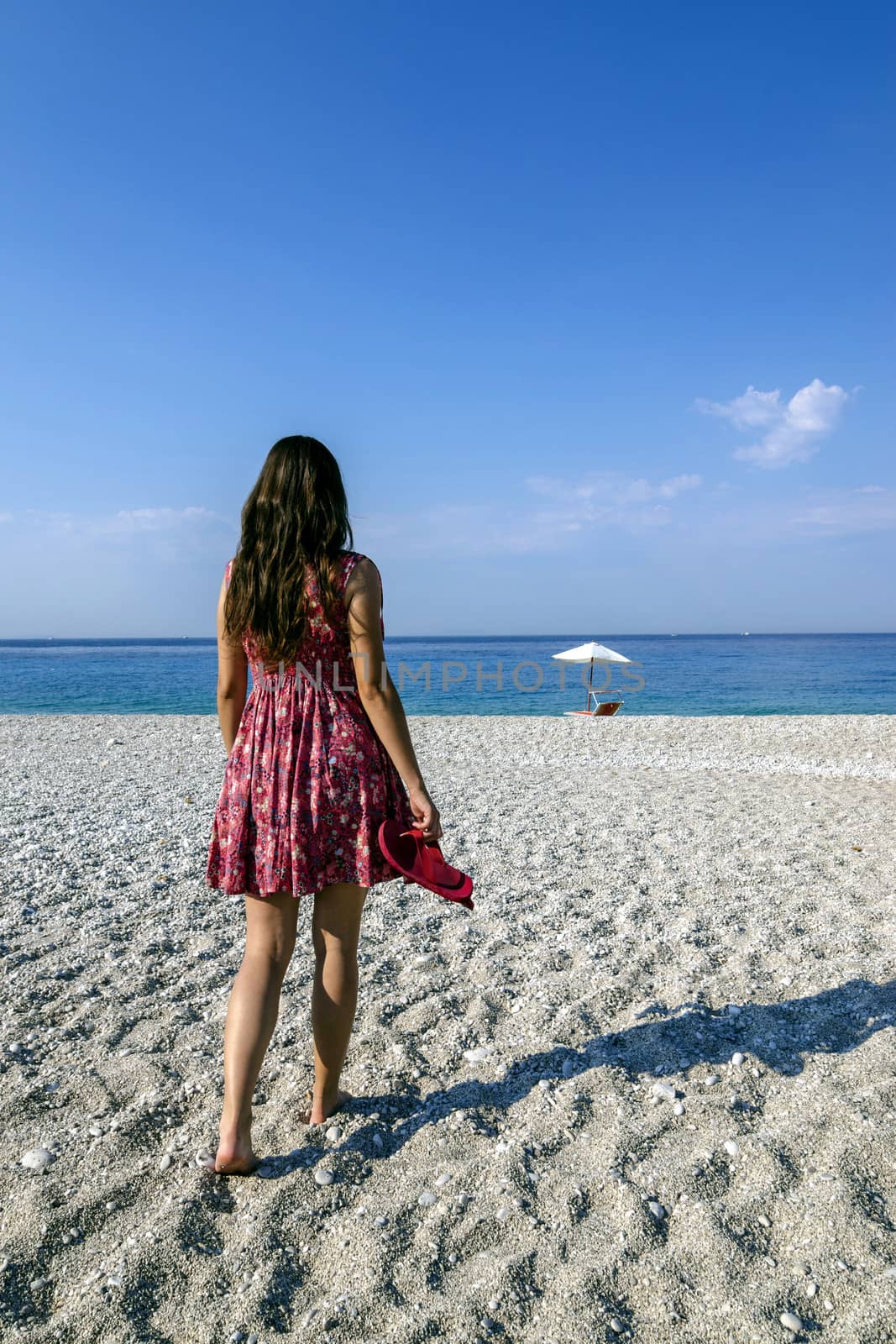 Girl on a beach walking towards beach relax place.