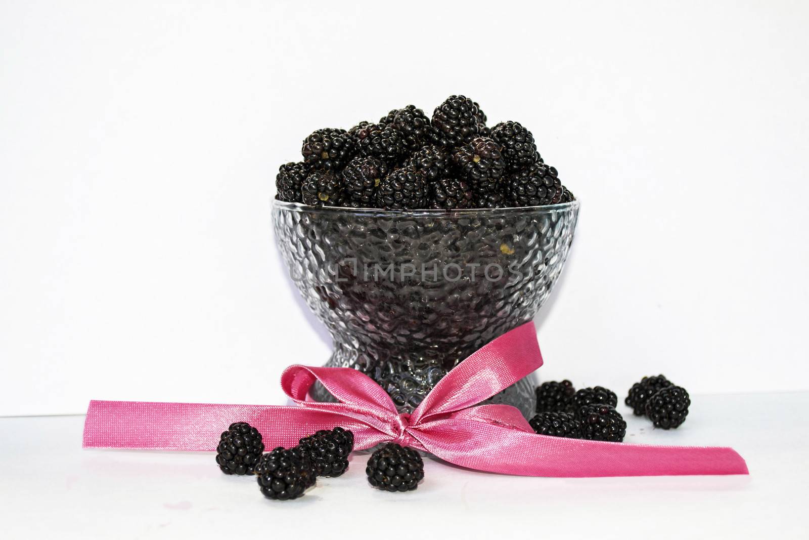 blackberry dessert in a glass with a pink ribbon