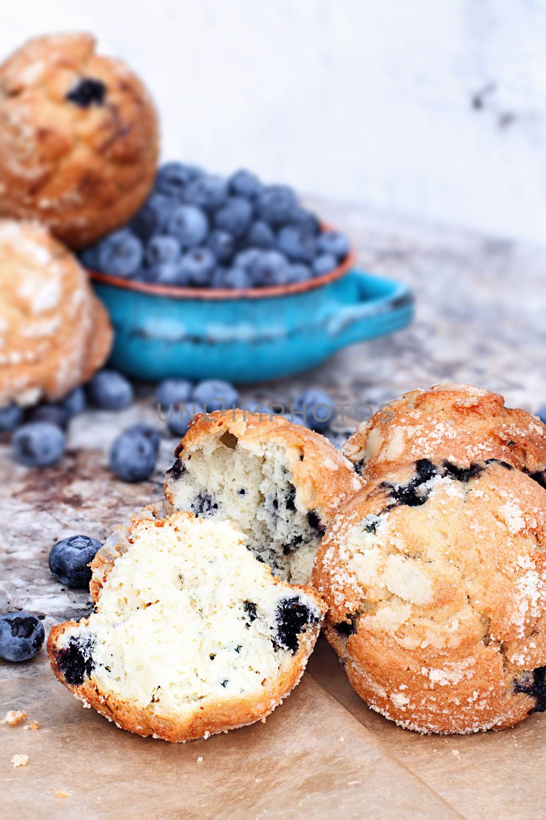 Delicious homemade blueberry muffins with fresh blueberries in the background.