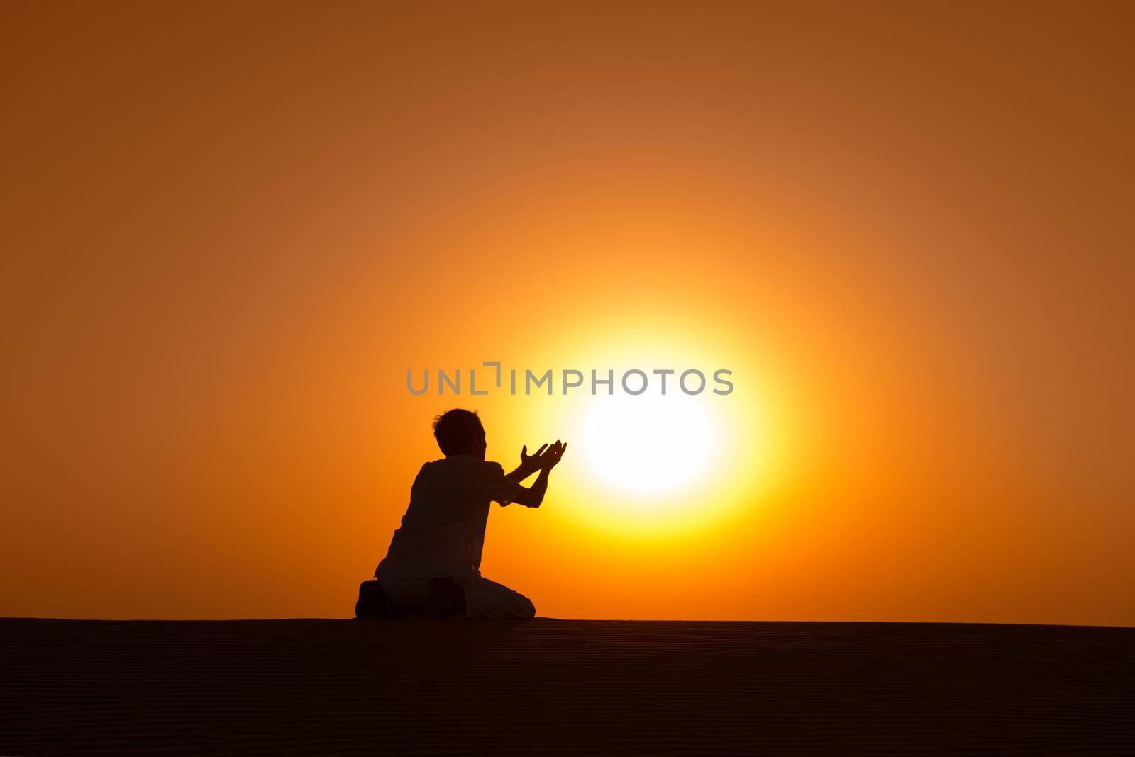 Man silhouette kneel and pray for help with gold sunset sun on background