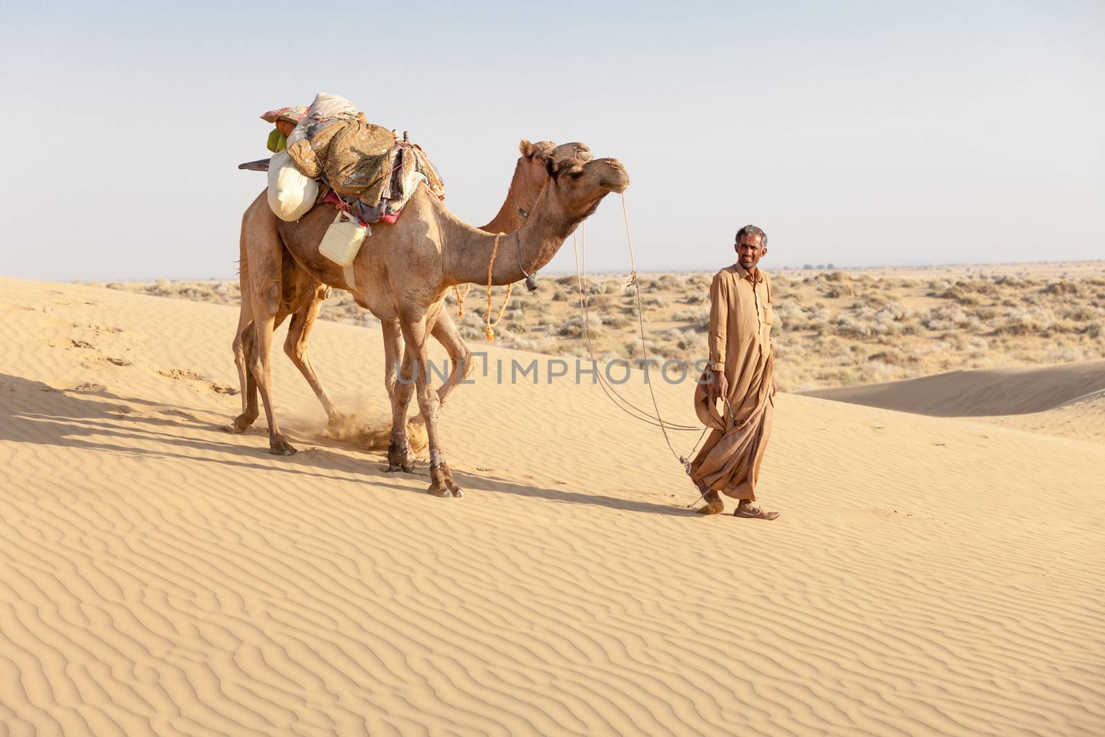 Bedouin and camels in sand dunes in desert by iryna_rasko