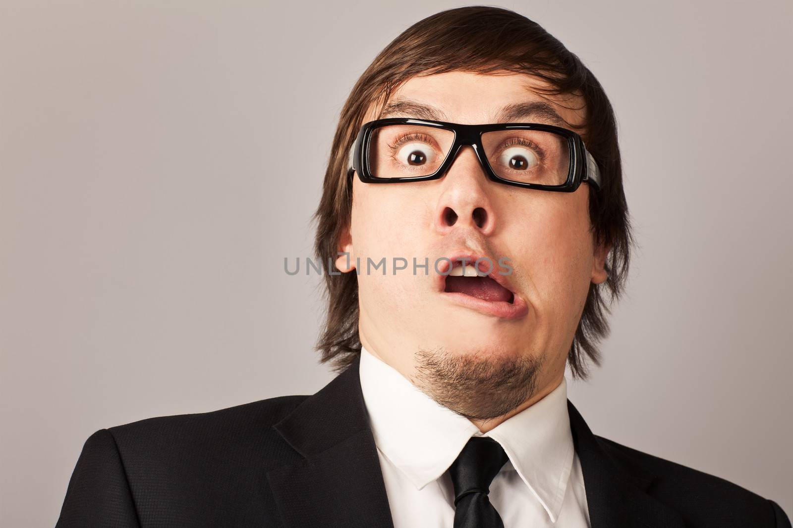 Close-up portrait of shocked businessman, hearing some news. On a gray background