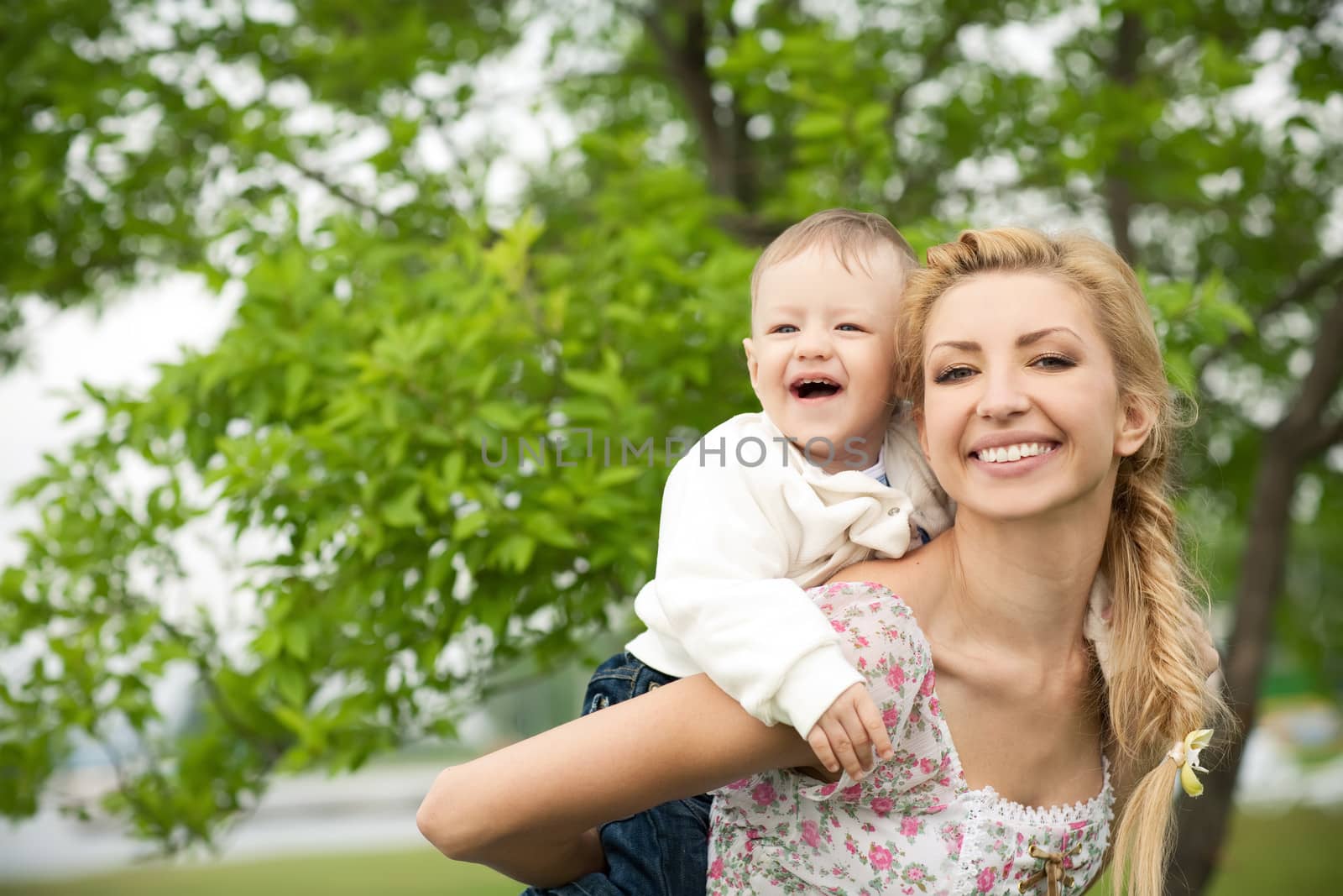 happy baby with mother on a background of green leaves. Much of copyspace