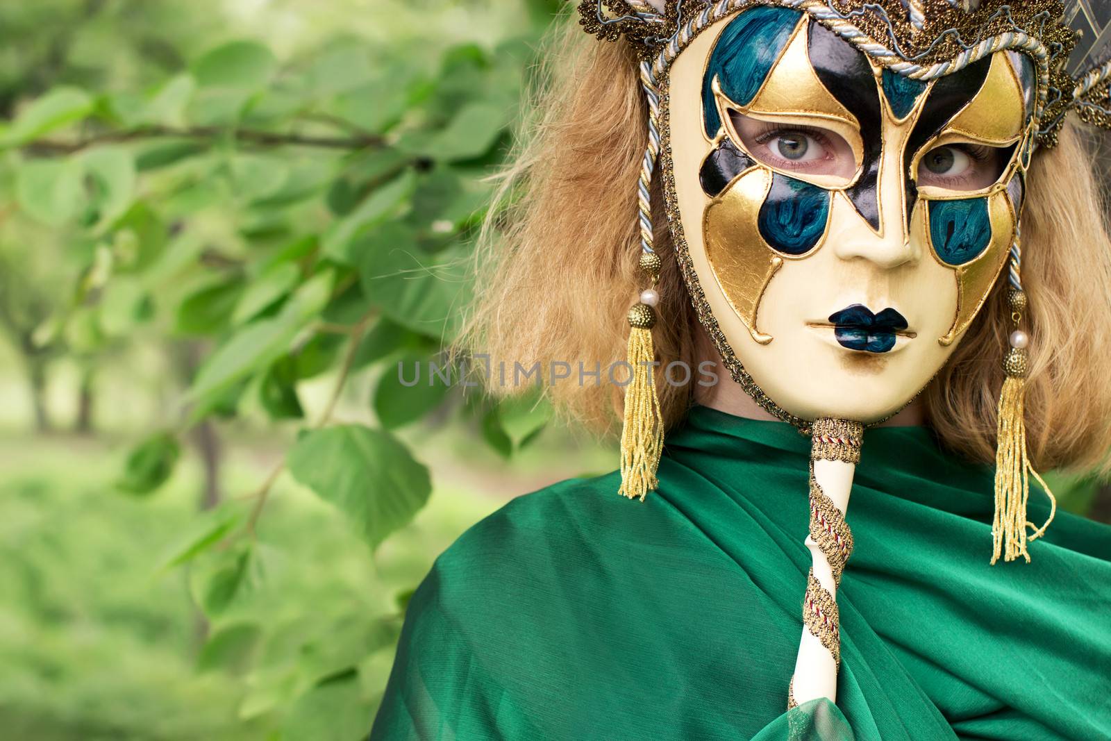 Beautiful woman in carnival mask over foliage background by deamles